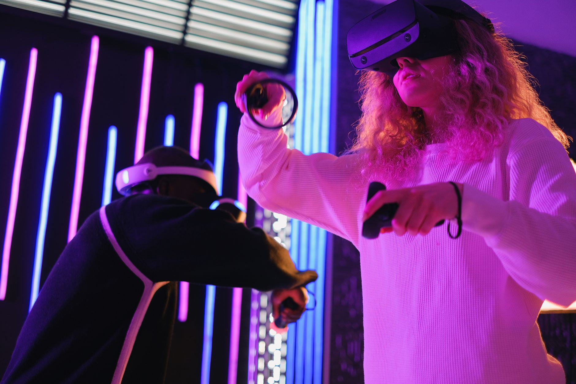 Two people enjoying an immersive VR gaming experience indoors with neon lights.