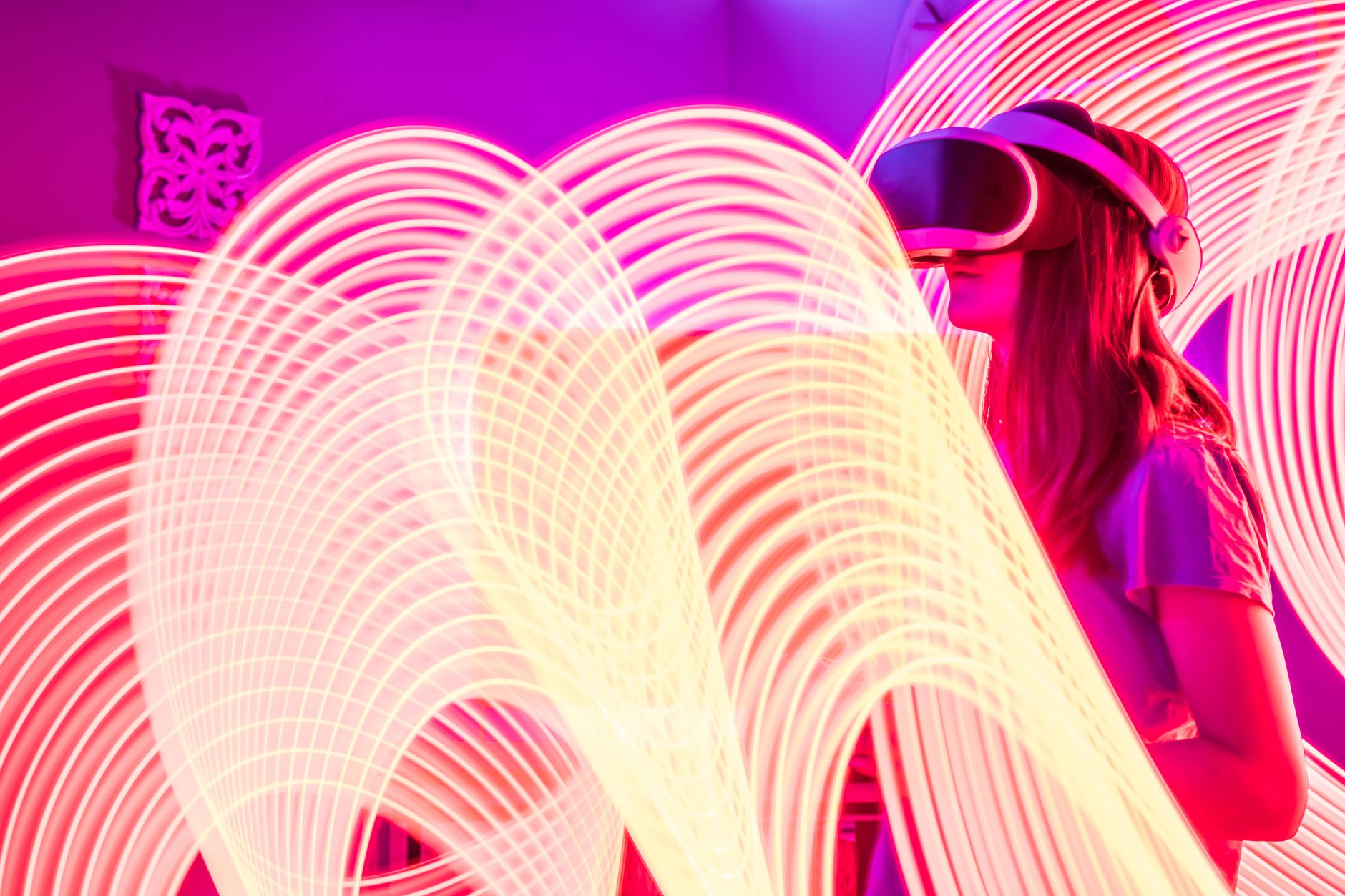 Woman wearing VR glasses surrounded by vibrant neon light trails for a futuristic experience.