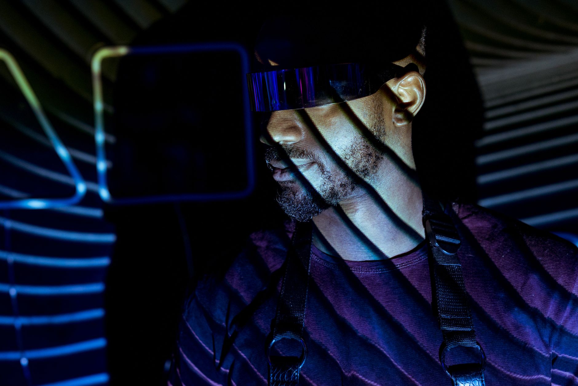 Futuristic portrait of a man wearing goggles with UV light patterns creating a vivid visual effect.