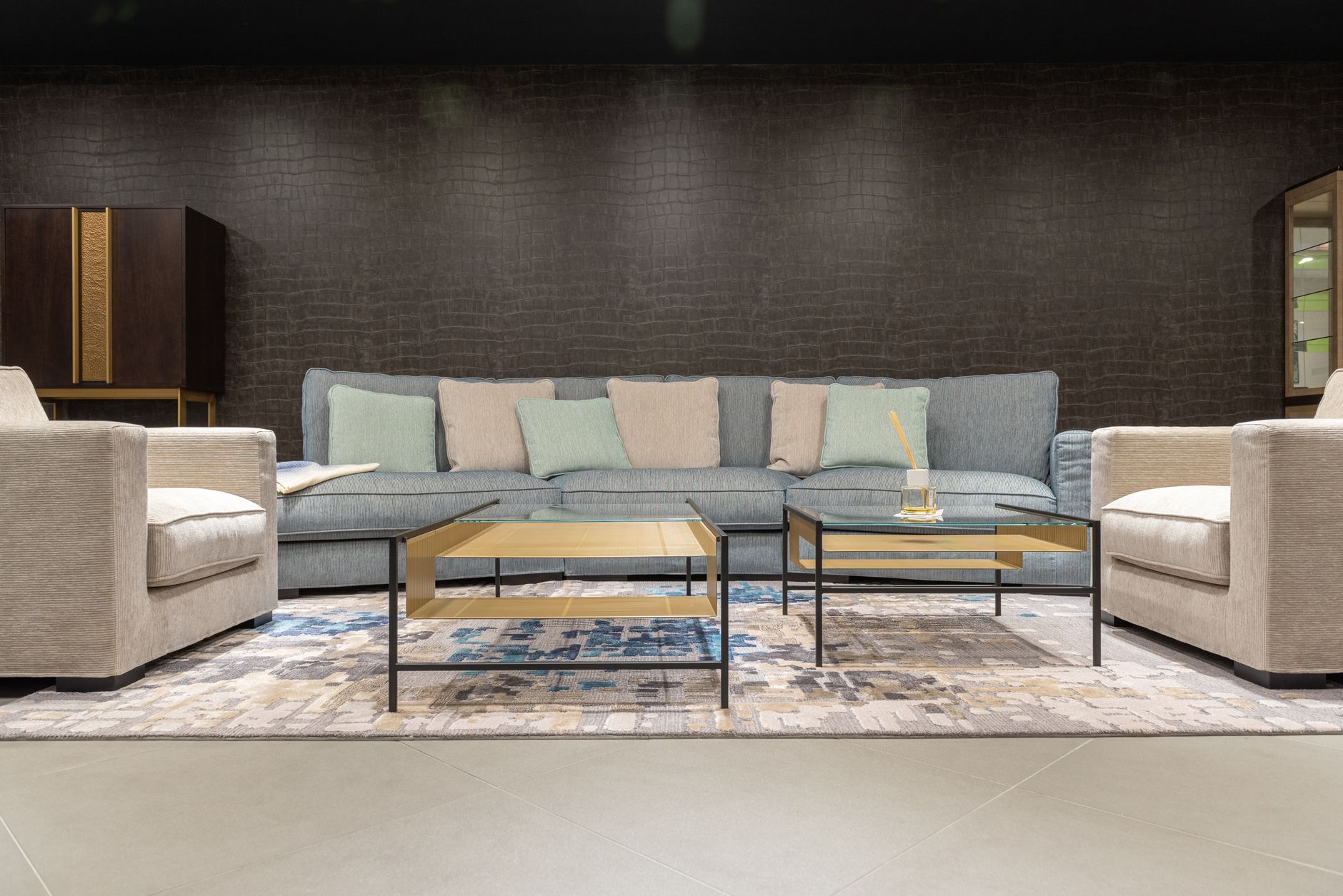 Comfortable gray sofa with colorful cushions and armchairs near tables on carpet in modern living room with dark wall