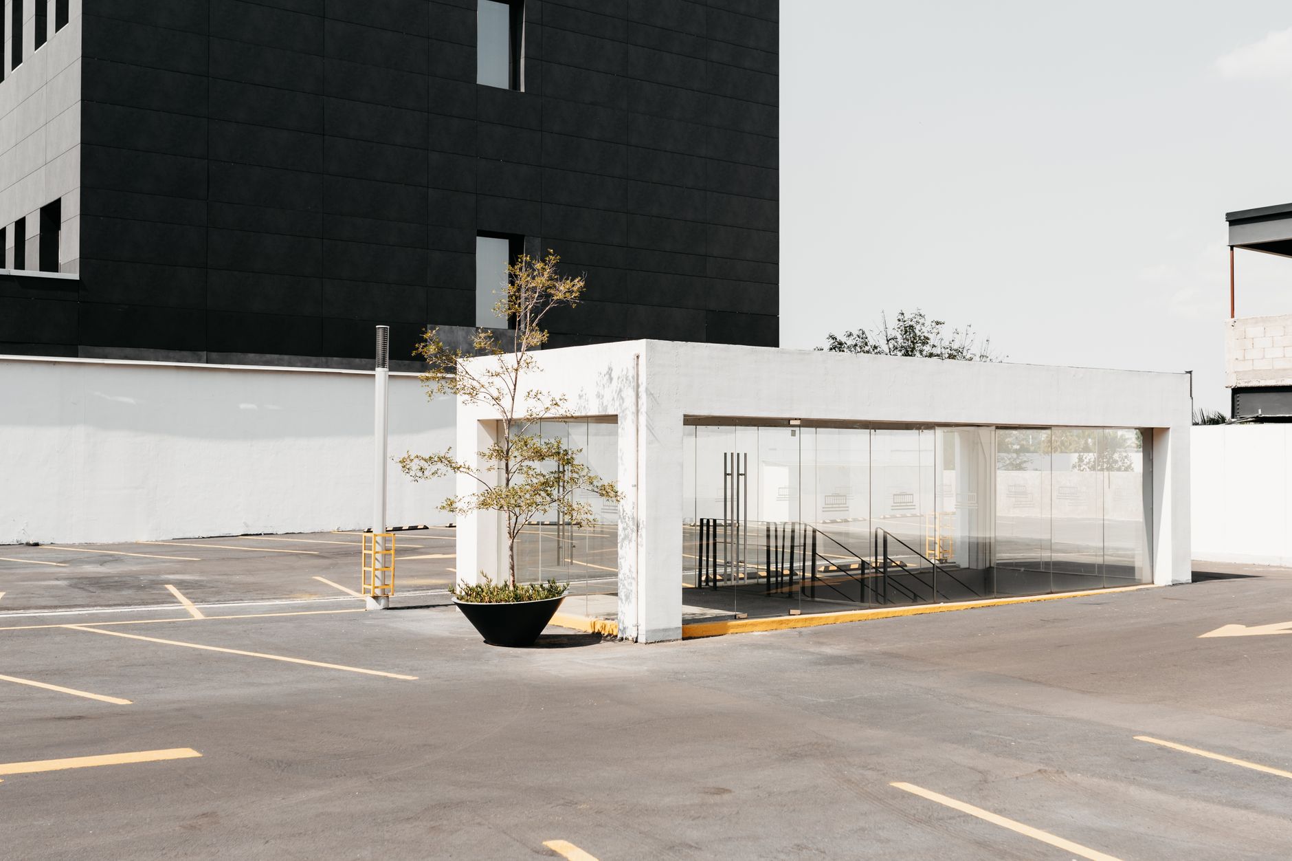 Empty parking with entrance to underpass near modern residential building in sunny day
