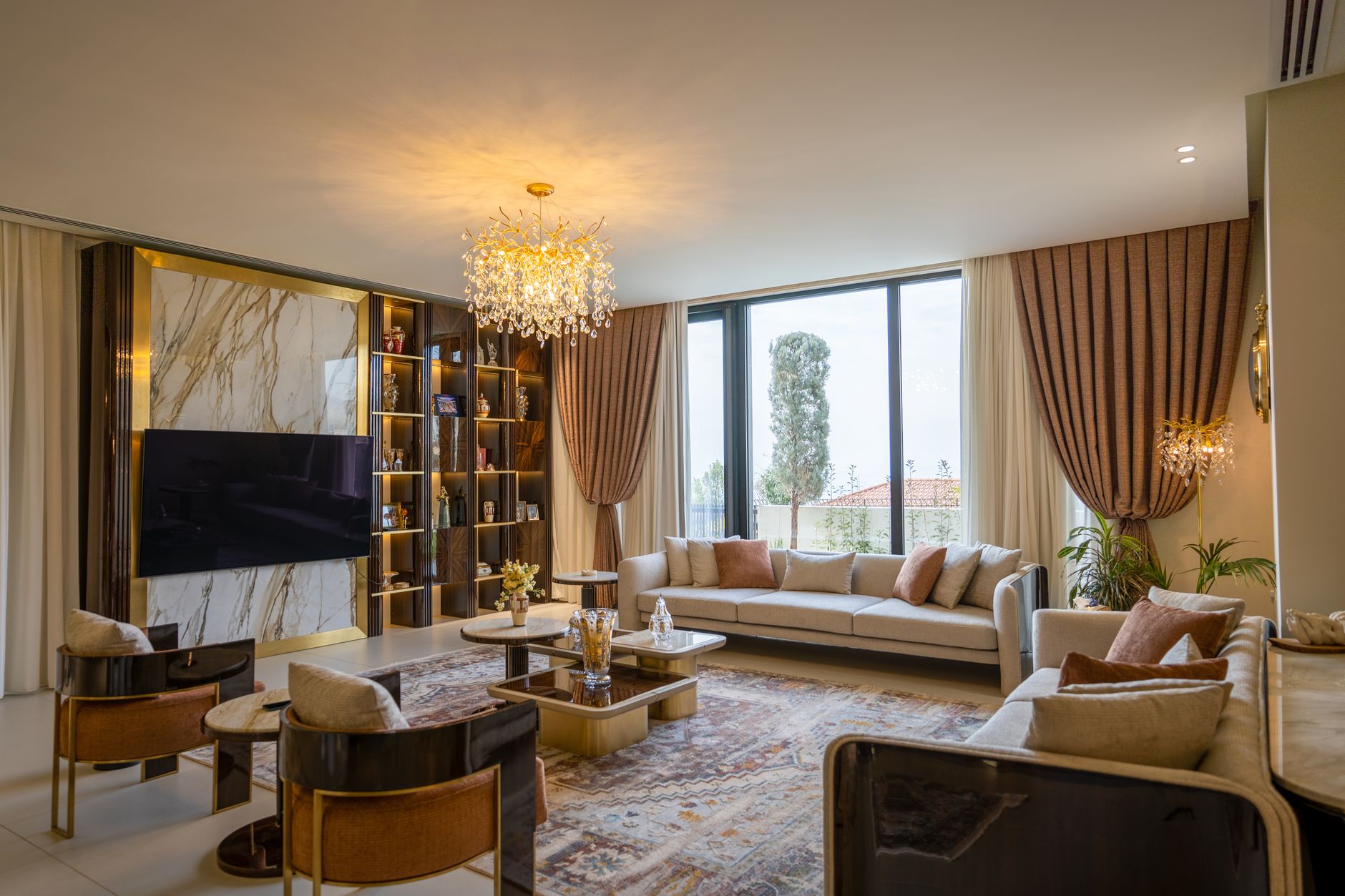 Spacious modern living room featuring elegant sofas, chandelier, and a large window view.