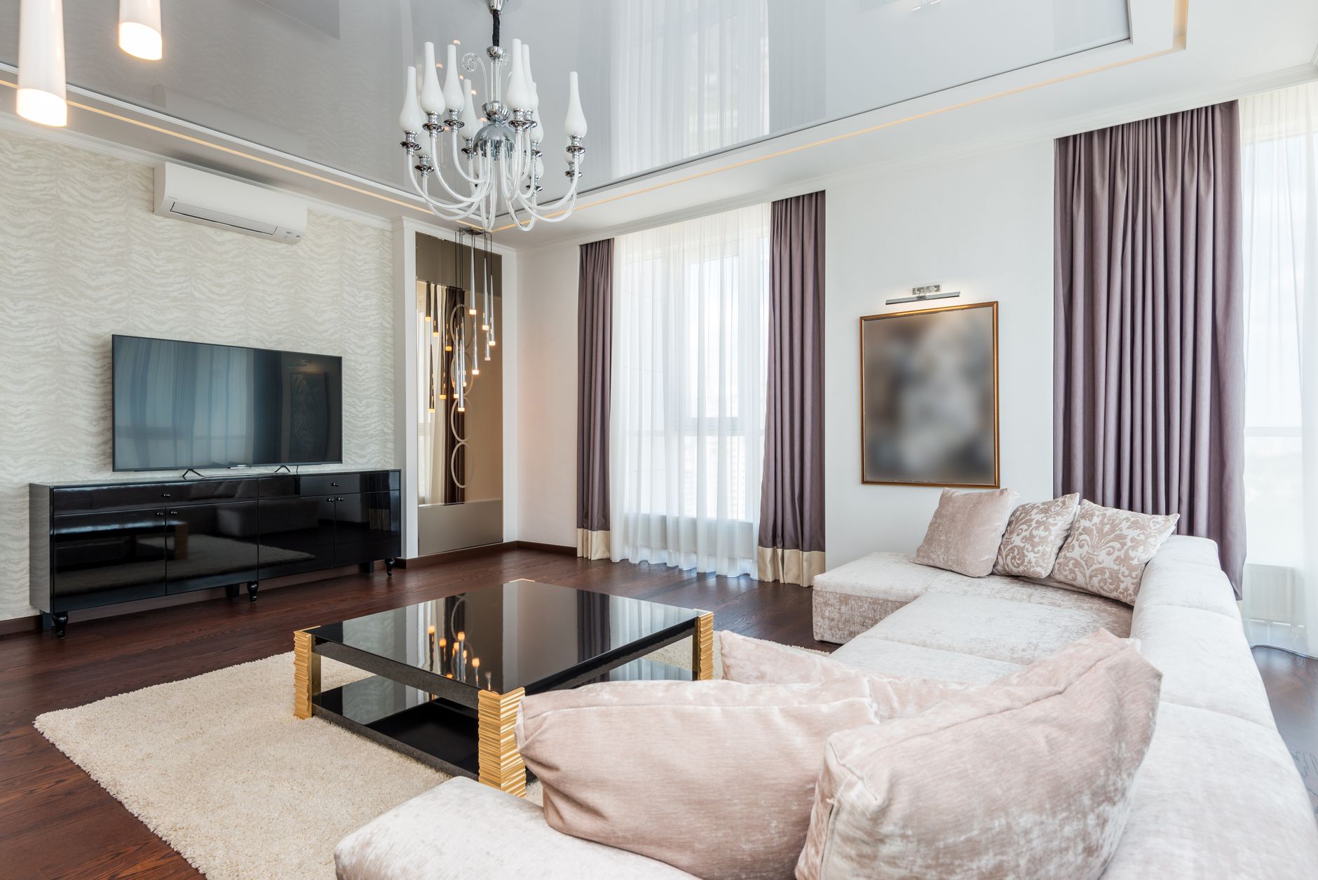 A sophisticated modern living room featuring a chandelier, plush furniture, and elegant decor.