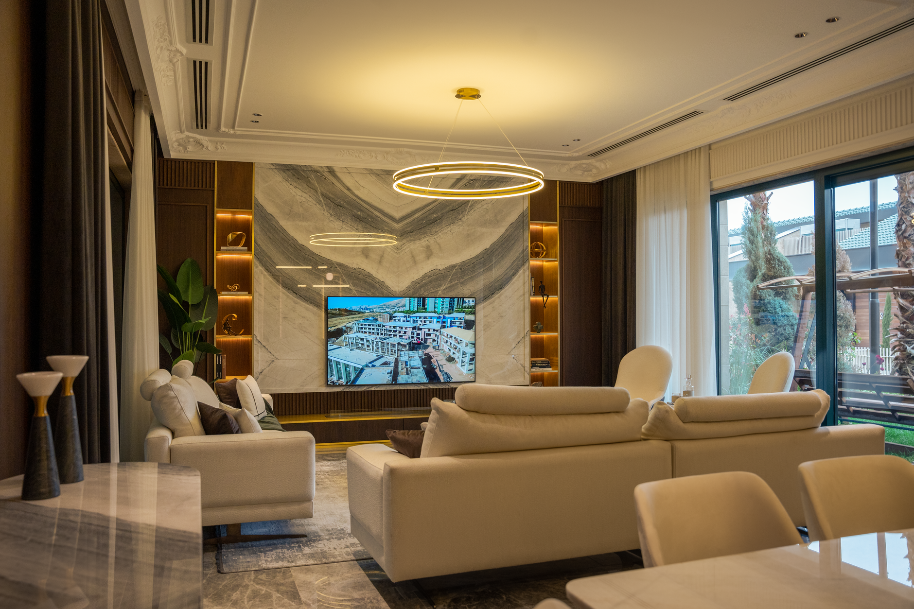 Luxurious contemporary living room showcasing modern furniture, lighting, and decor with large windows.