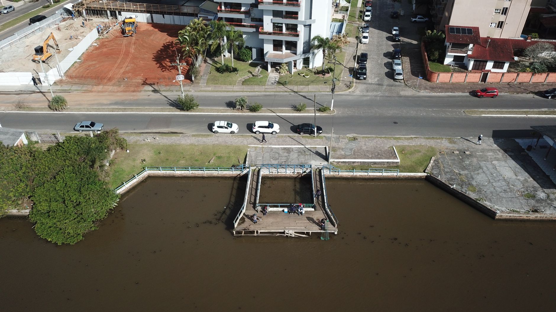 Aerial view of a dock near an urban landscape with parked cars and buildings.