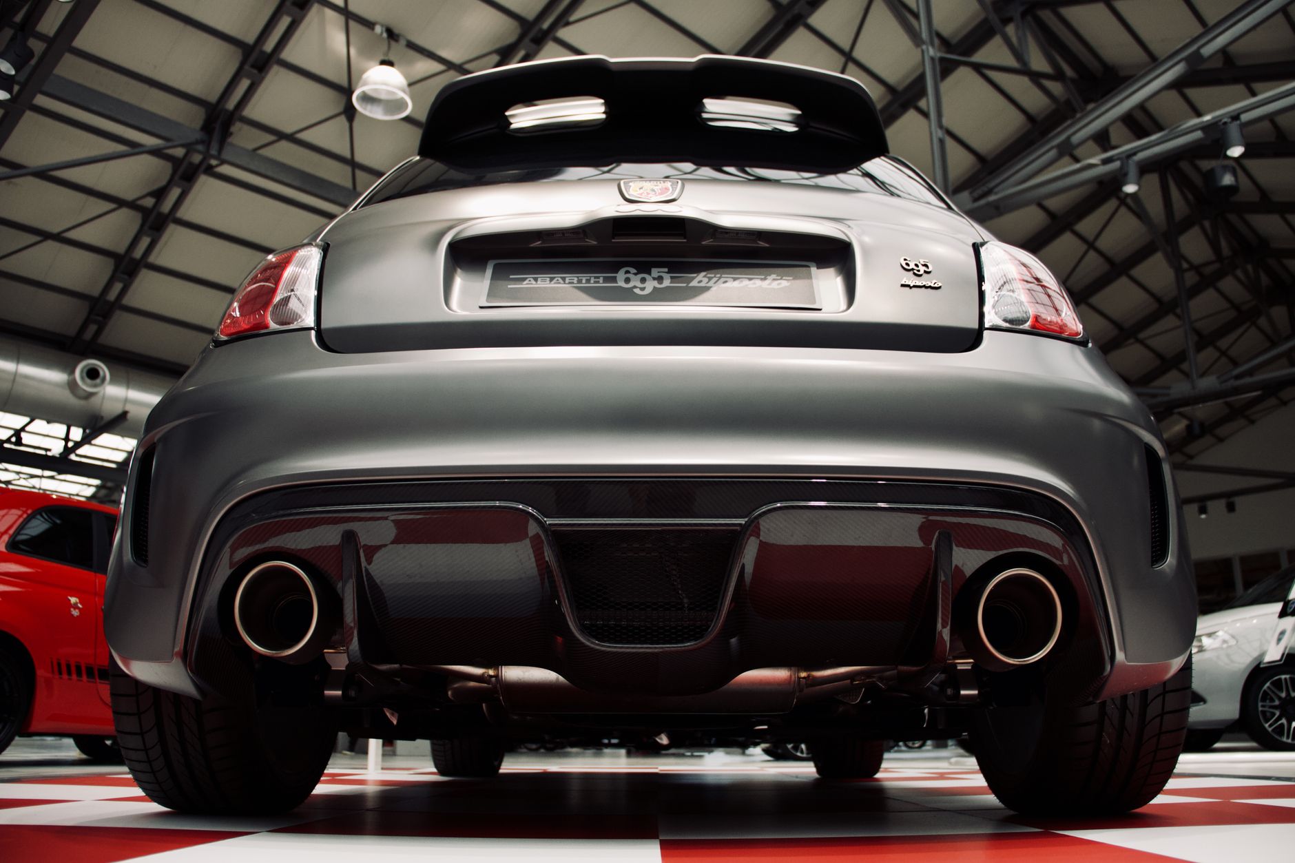 Low angle shot of a luxury sports car's rear with an exhaust, indoors.