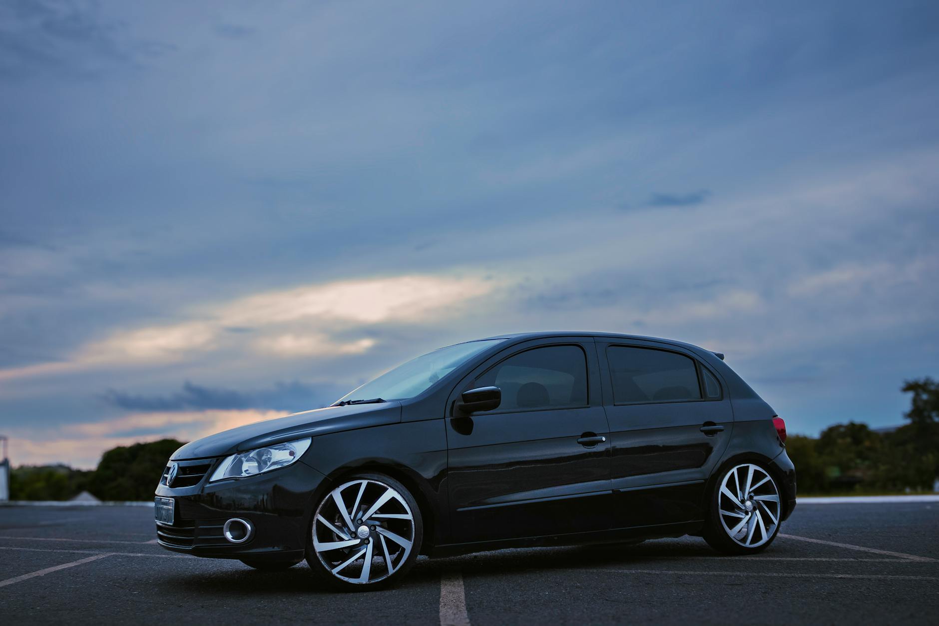 Sleek black hatchback parked in Brasília at twilight against a dramatic sky.