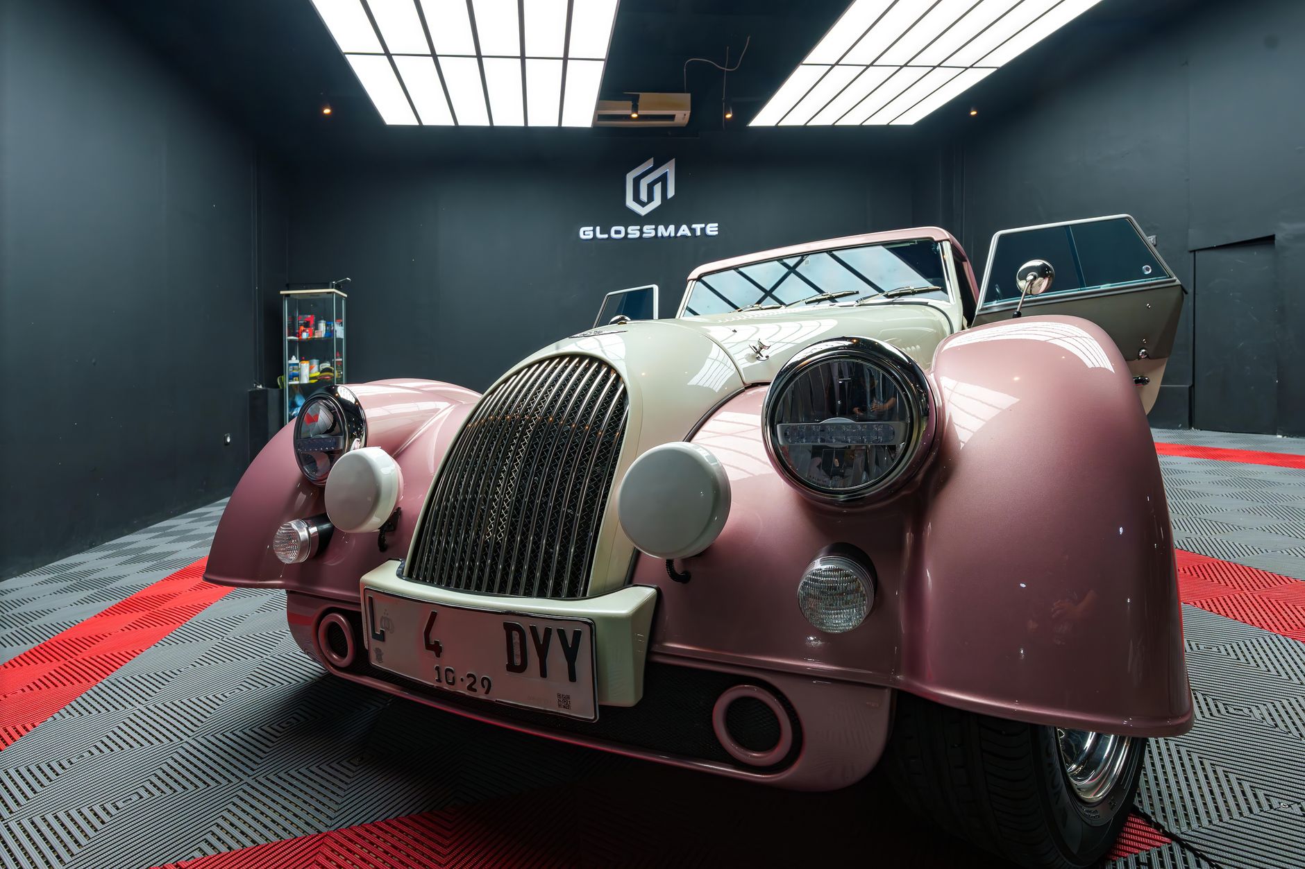 A classic vintage convertible inside a stylish showroom with modern lighting.