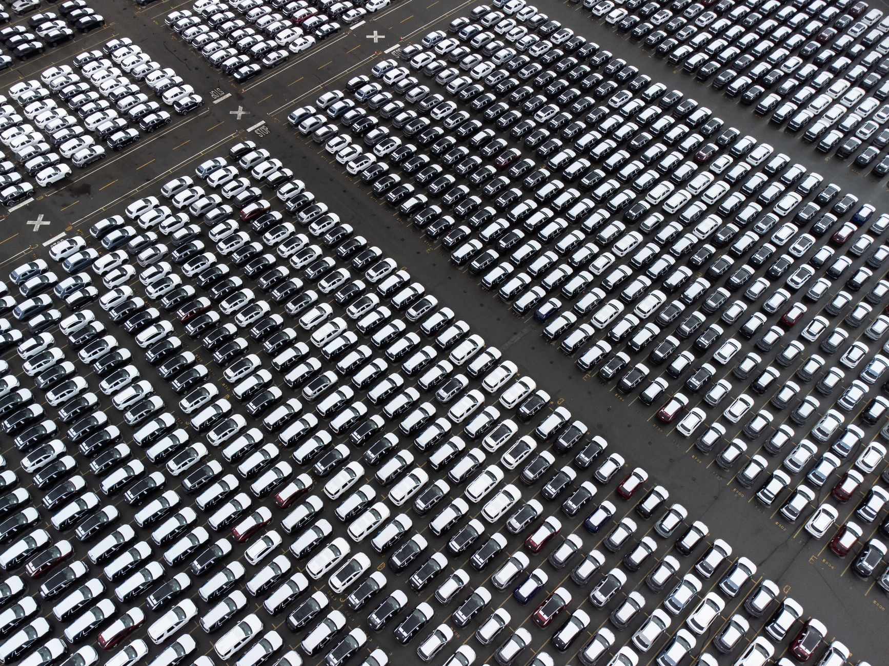Aerial perspective of an organized car parking lot with rows of vehicles arranged in a grid pattern.