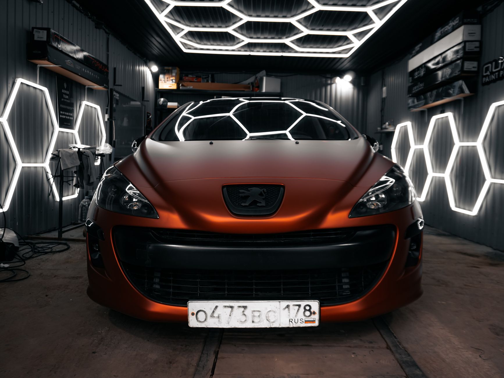 A matte red car with striking hexagonal lights in a modern garage setting.