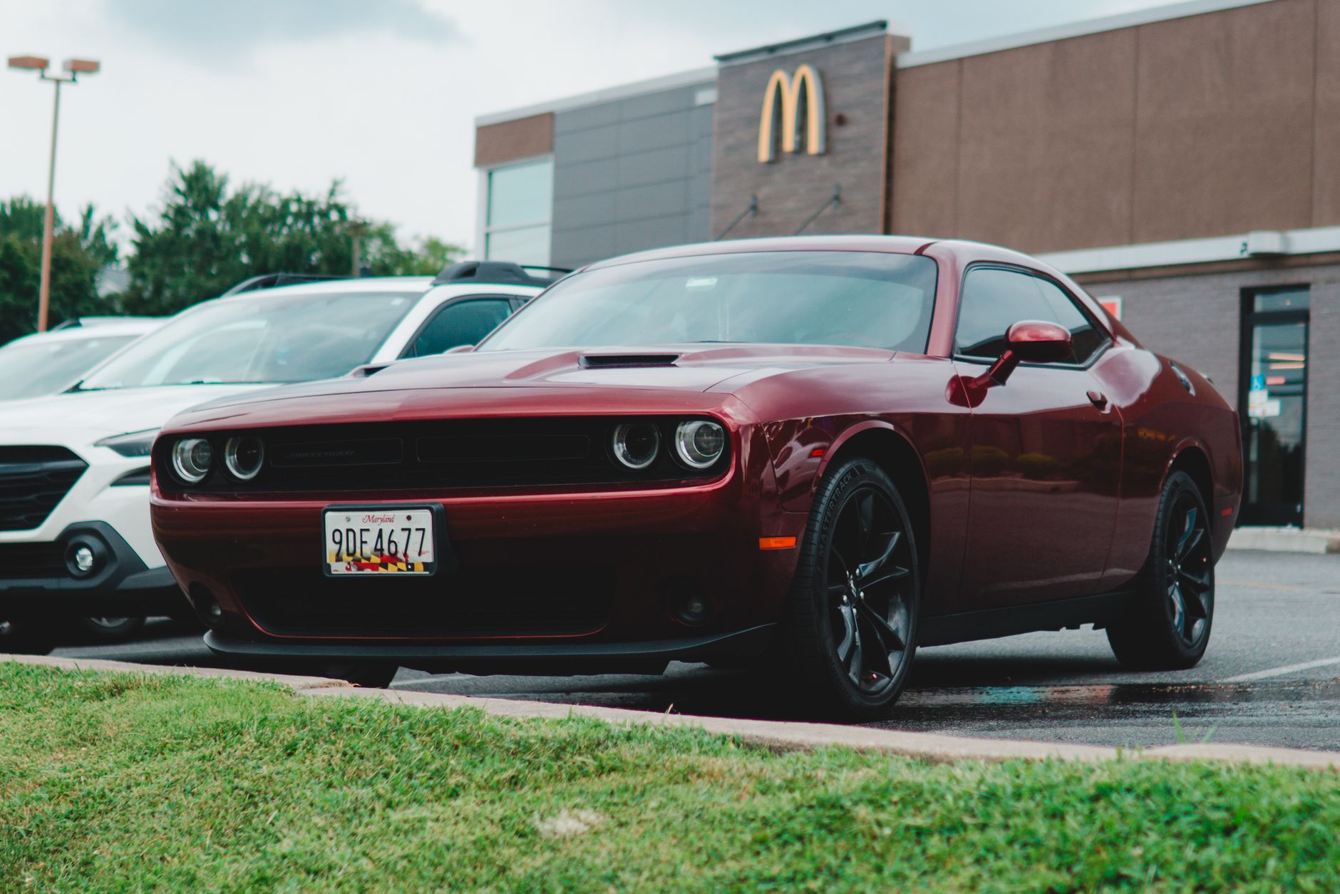 Red Dodge Challenger parked in a McDonald's lot, showcasing its sleek design.