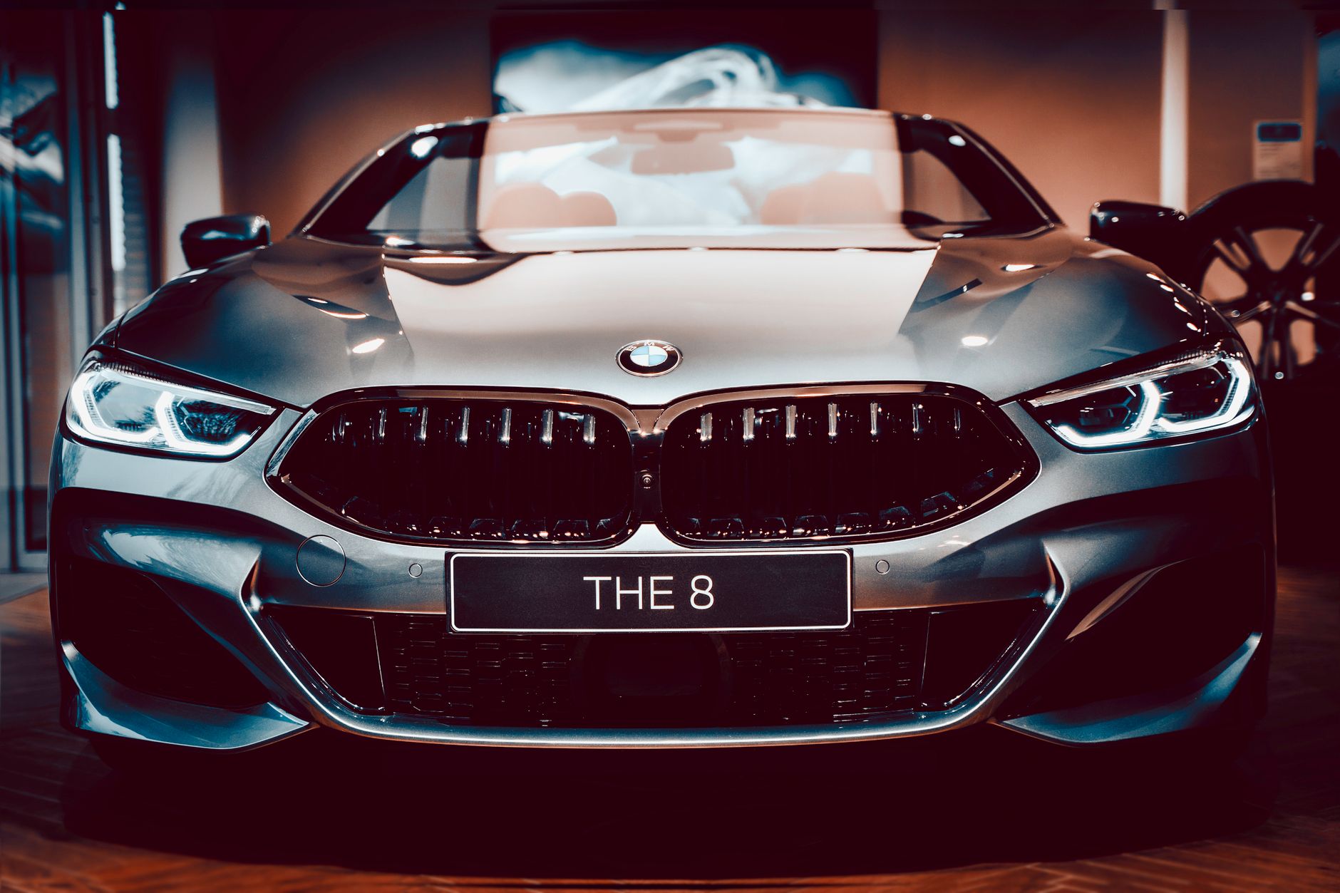 Close-up frontal view of a sleek silver BMW 8 Series convertible displayed in a showroom.