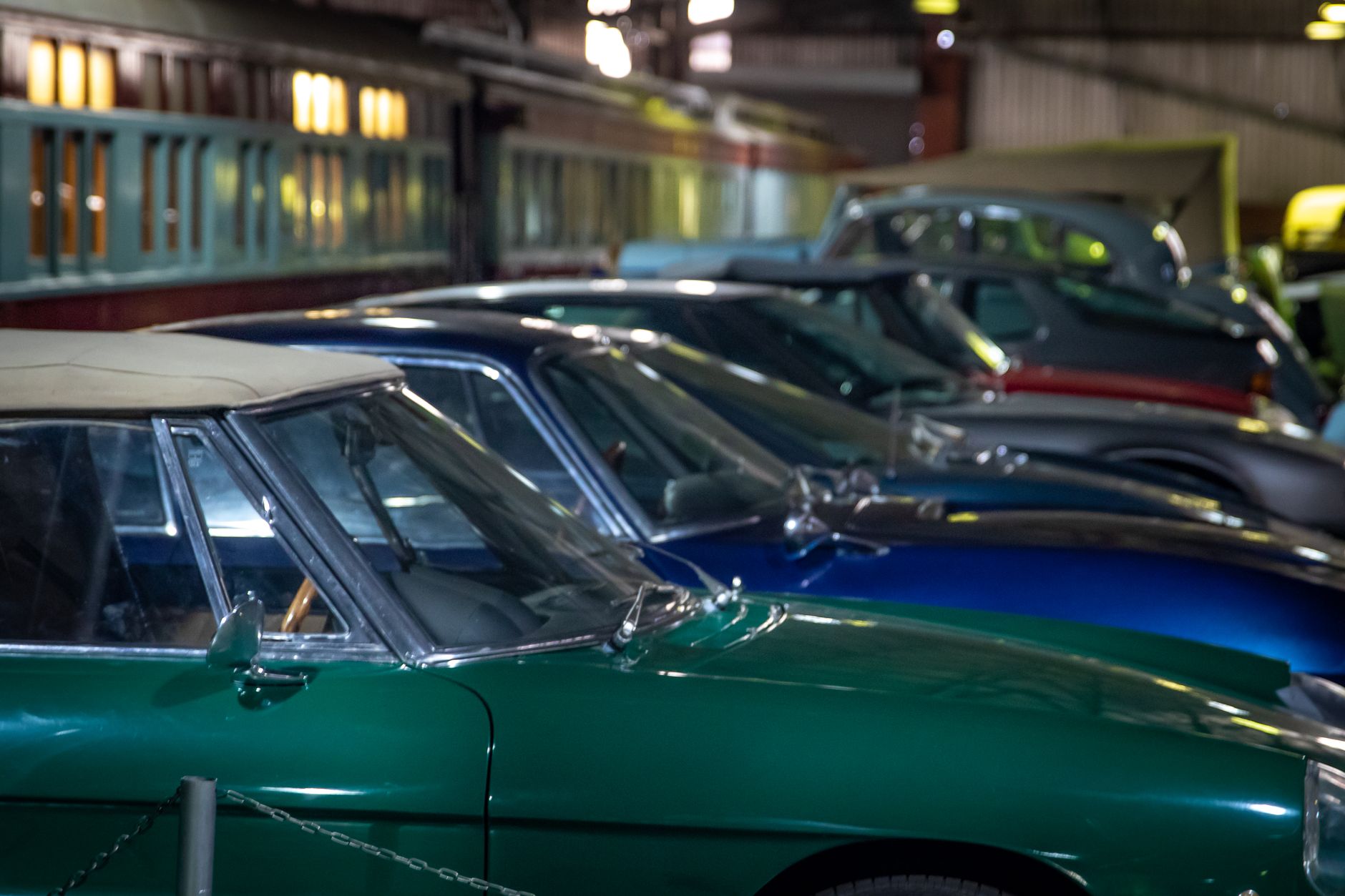 Row of classic vintage cars parked indoors, showcasing elegance and history.