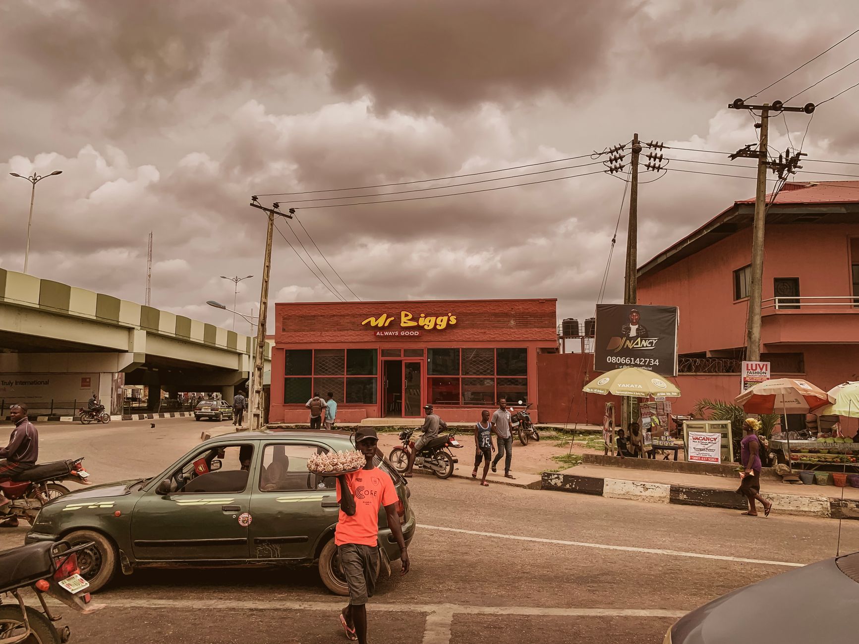 Urban view featuring Mr. Bigg's, cars, and people on a cloudy day.