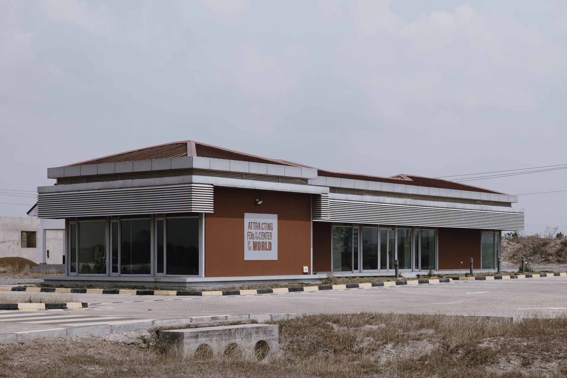 A modern commercial building with reflective glass in a deserted outdoor area.