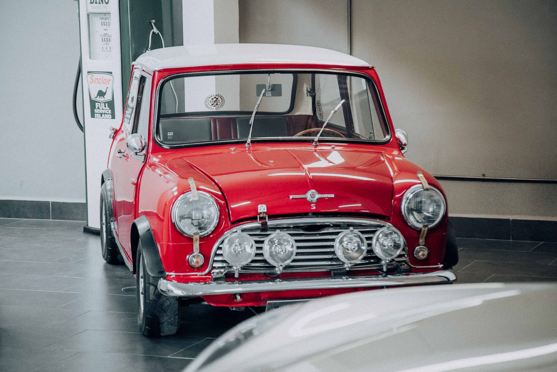 A classic red Mini Cooper displayed indoors, exuding vintage charm and retro style.