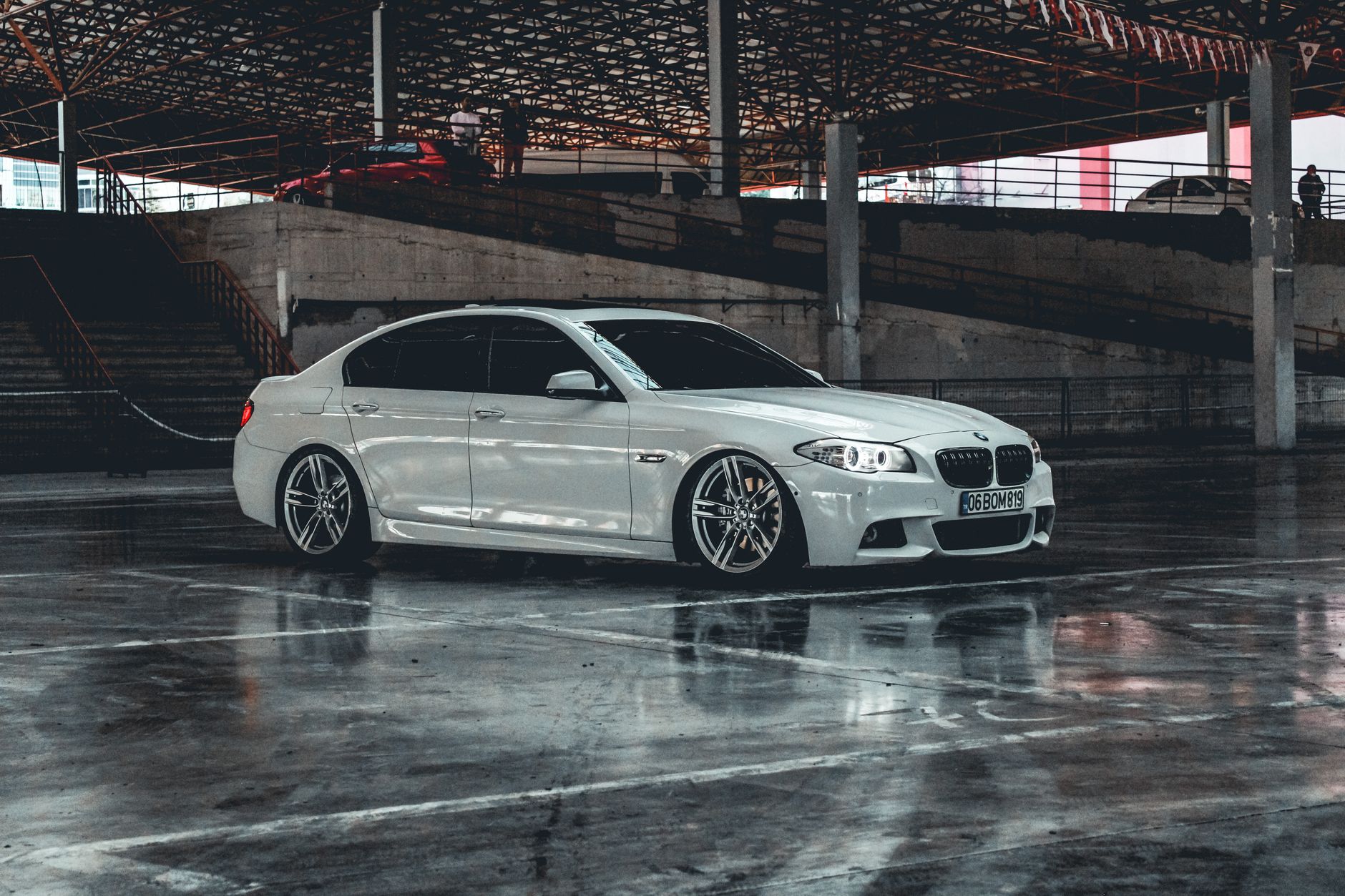 White luxury car parked in an urban garage, showcasing modern design and reflection.