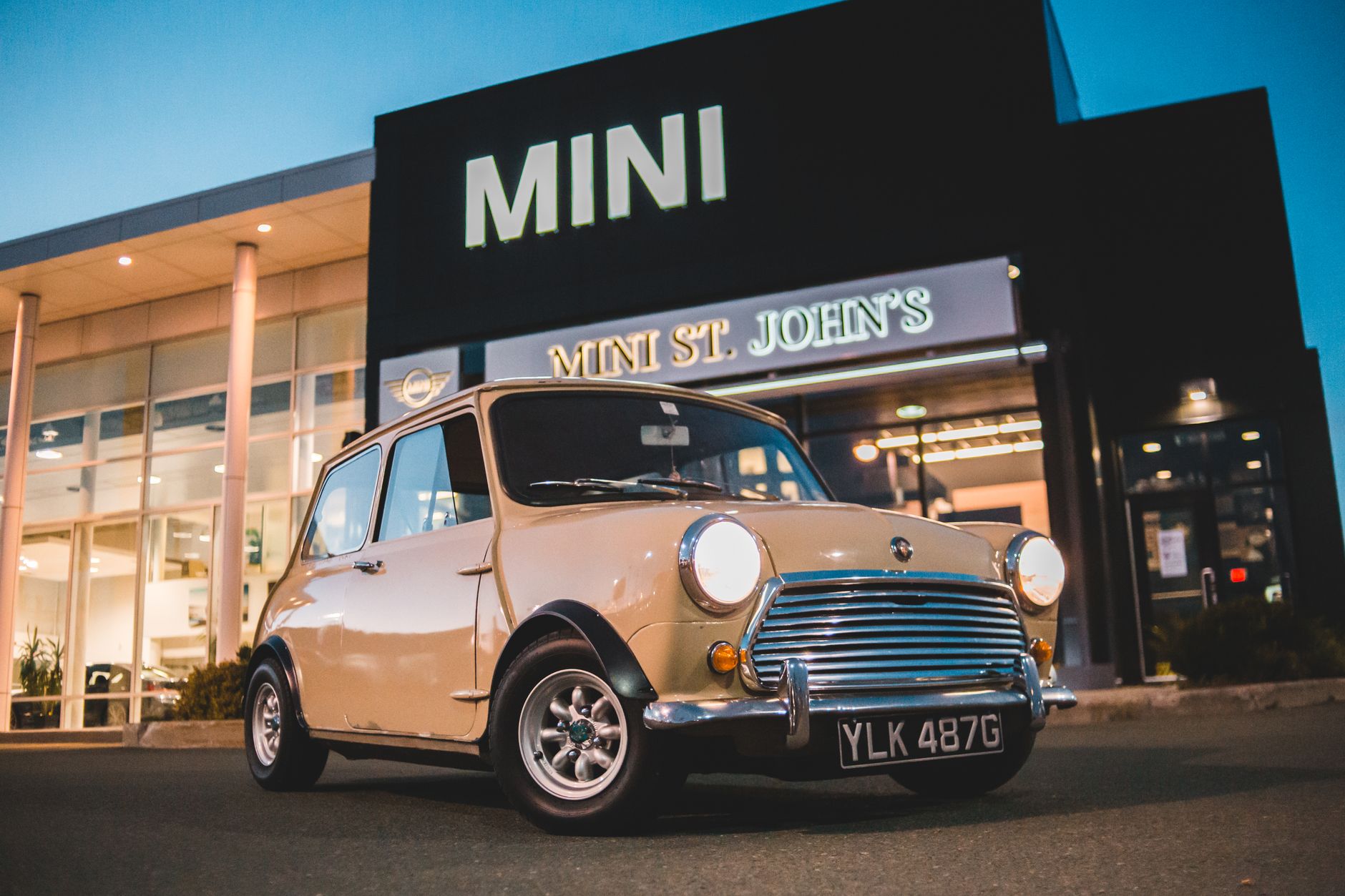 Ground level of luxury vintage car parked on street near modern building in evening