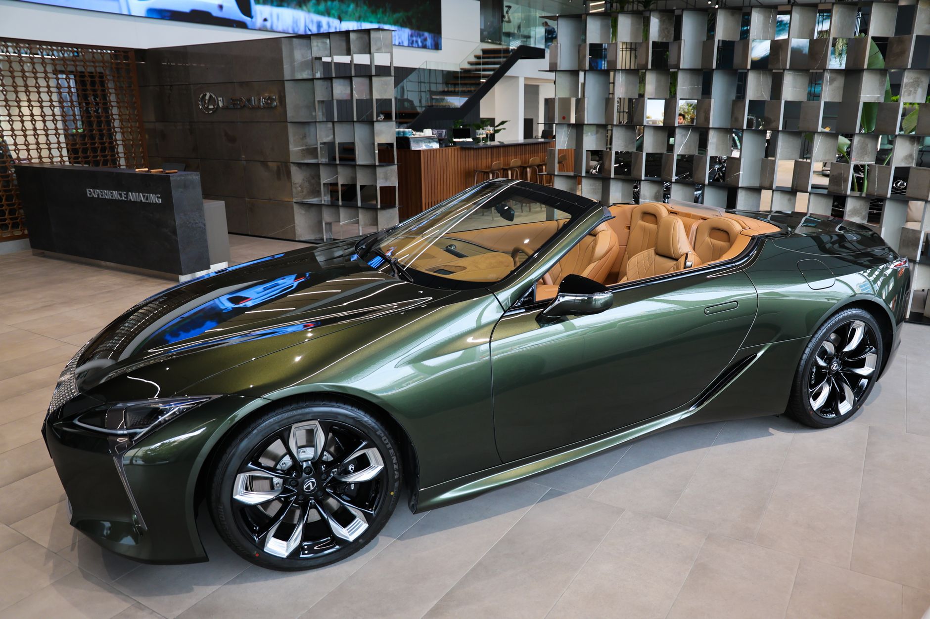 Luxury green convertible car displayed in an elegant showroom setting.