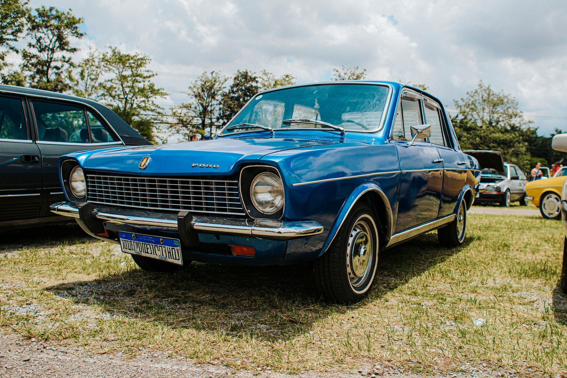 A classic blue Ford car parked outdoors at a vintage car show.