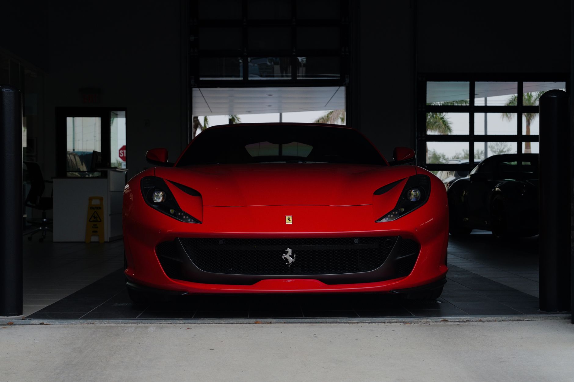 A striking red sports car parked in a contemporary garage setting, showcasing luxury design.