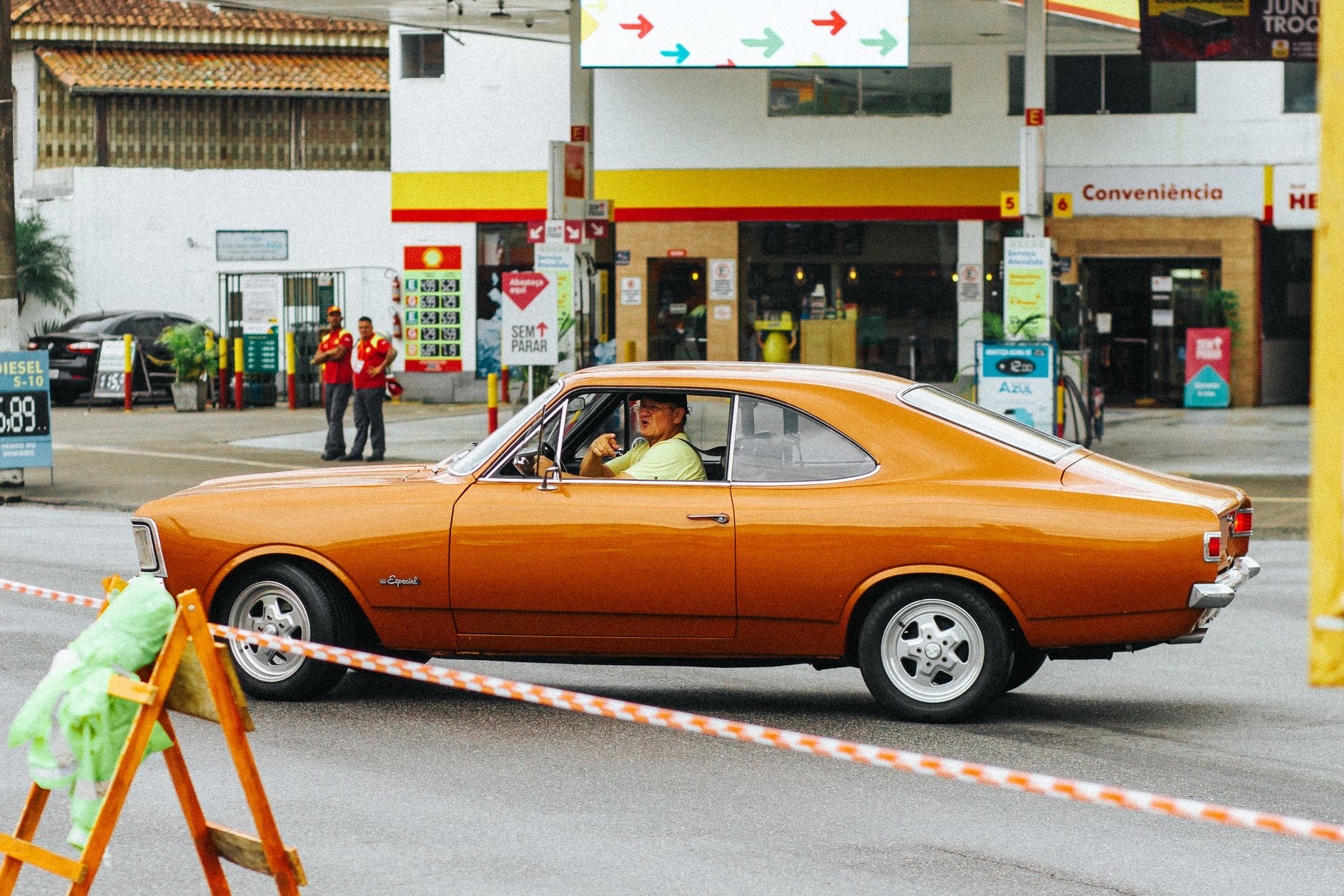 A classic orange Chevrolet Opala driven through a city street, showcasing vintage car culture.