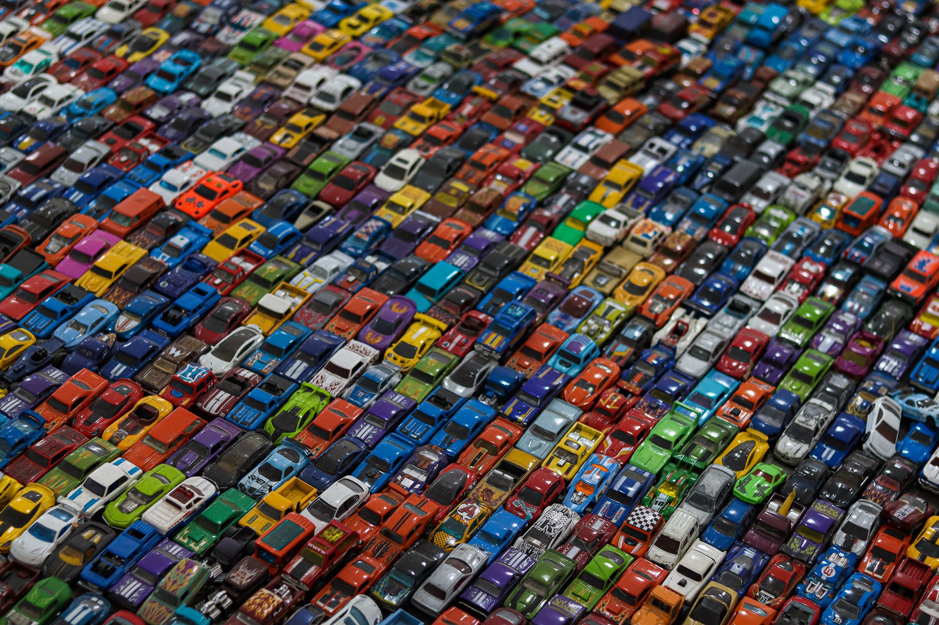 A stunningly vibrant collection of multicolored toy cars arranged in a dense, eye-catching mosaic pattern.