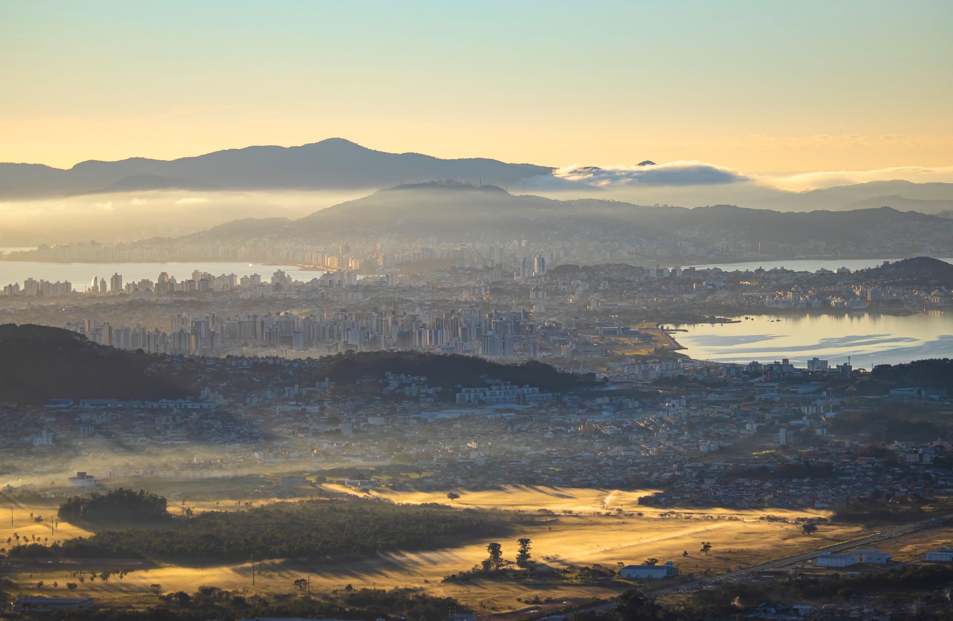 A stunning aerial view of Florianópolis, Brazil, at sunrise showcasing mountains and cityscape.