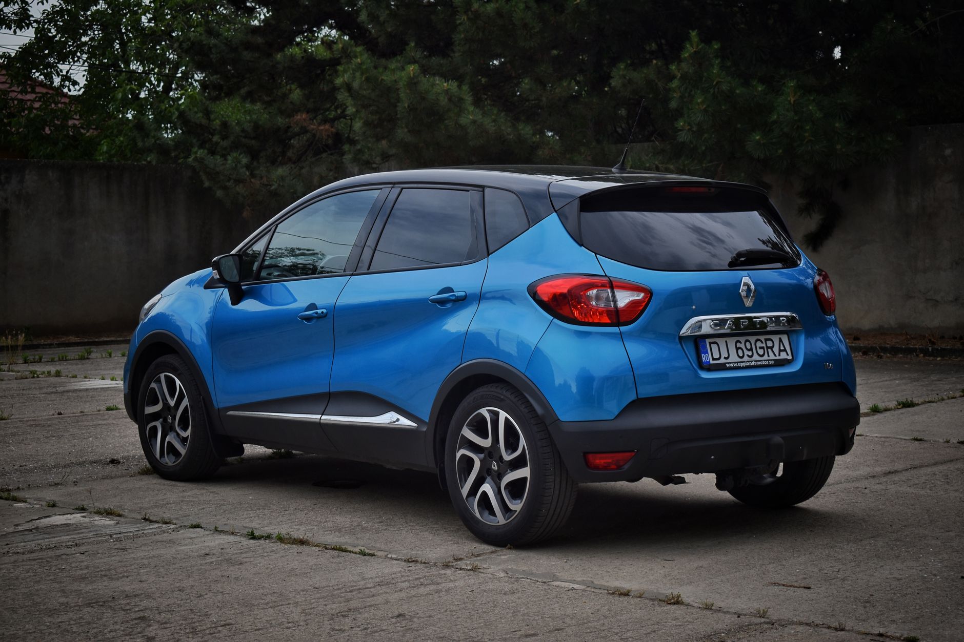 A sleek blue Renault Captur car parked on a concrete surface, outdoors.