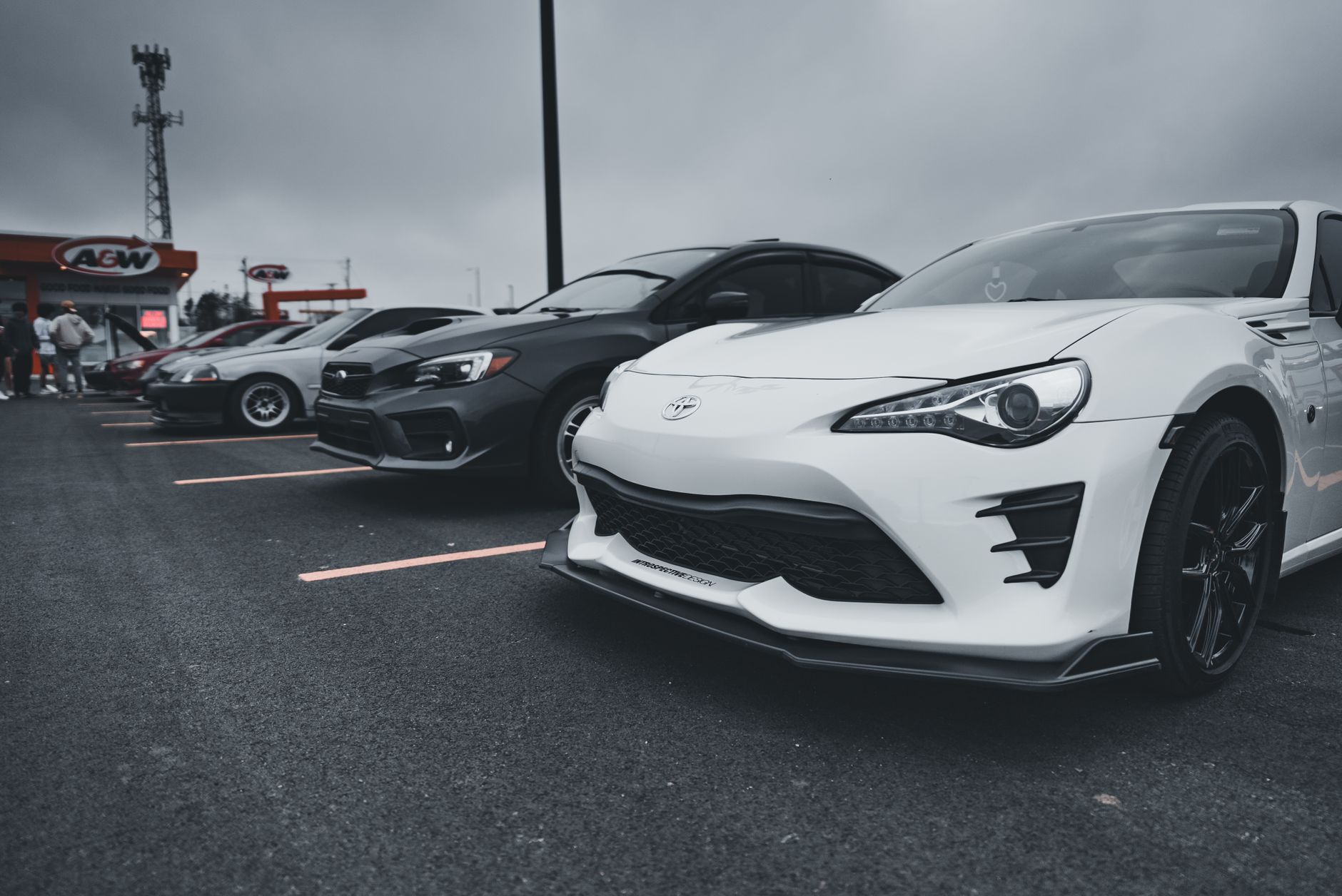 A lineup of stylish sports cars parked outdoors under a cloudy sky.