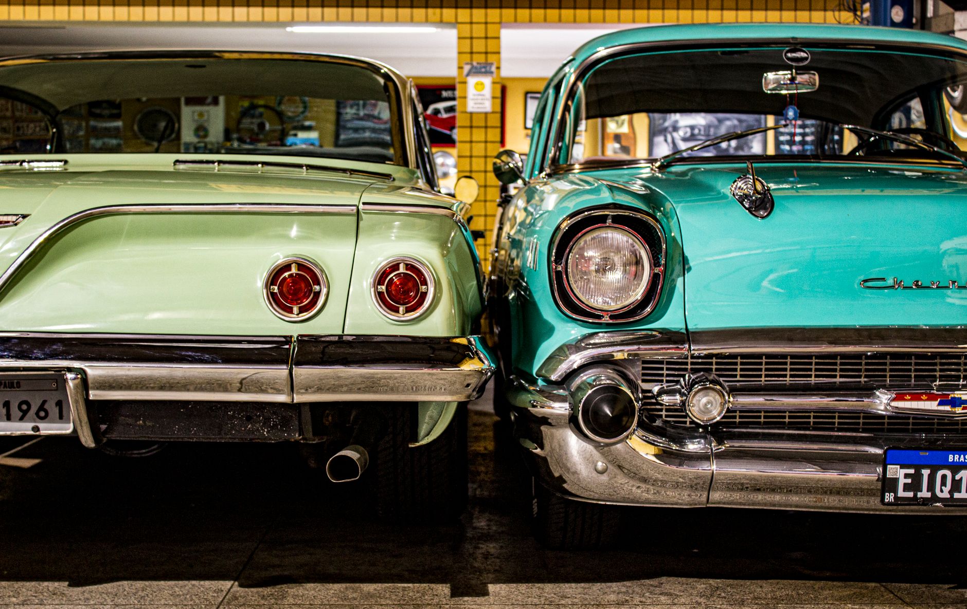Two vintage Chevrolet cars parked in a retro garage, showcasing their classic design and chrome details.