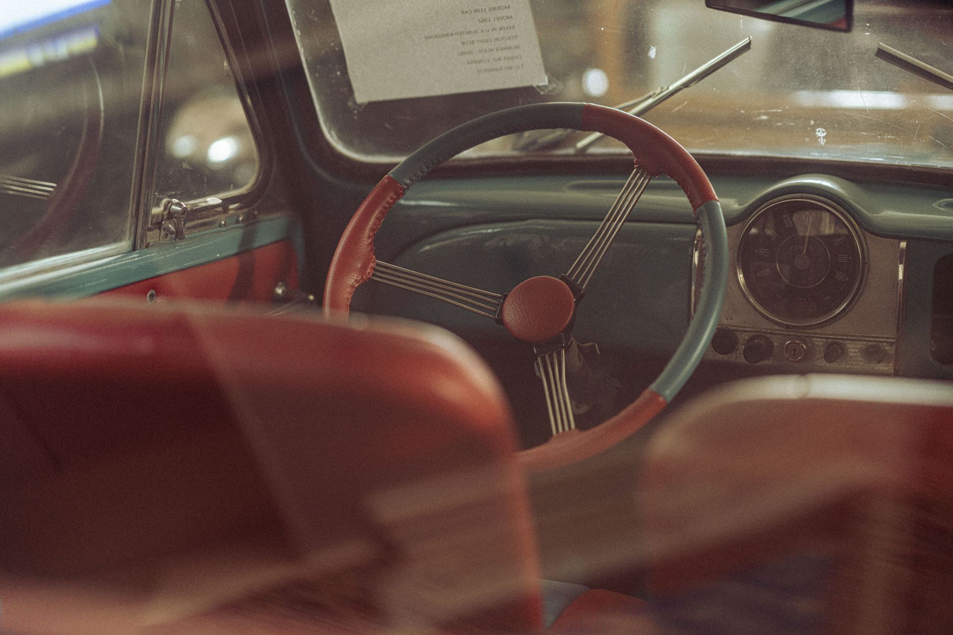 Retro car interior featuring red leather seats, classic steering wheel, and vintage dashboard.