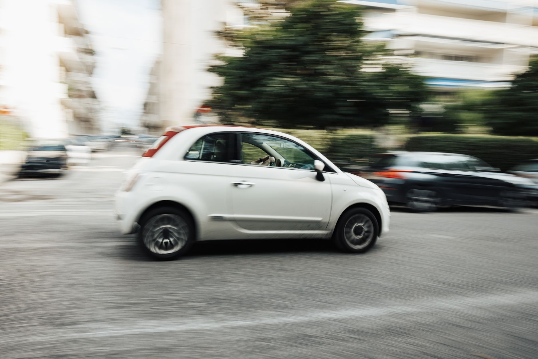 White car speeding through city street with motion blur effect highlighting fast motion.