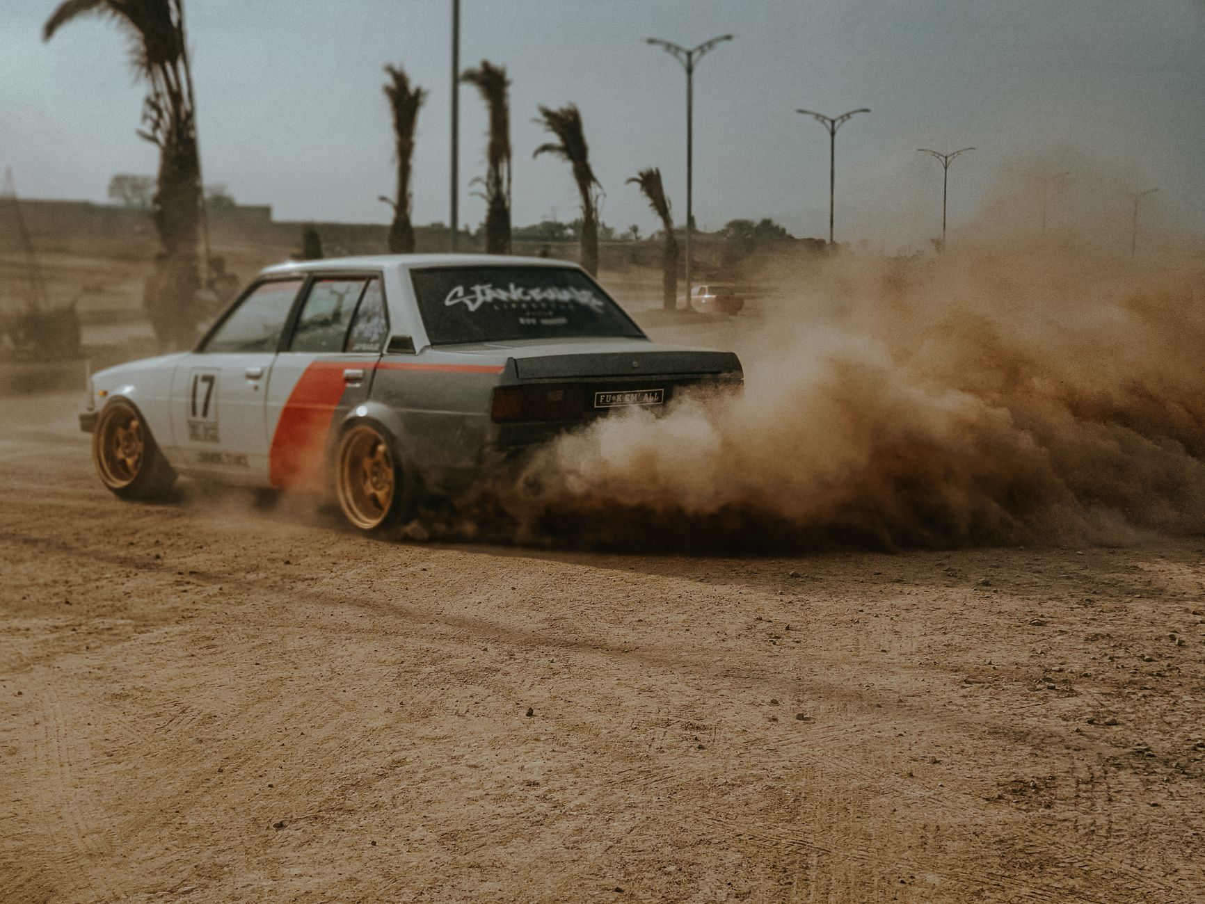 Vintage Toyota Corolla E70 drifts on a dusty track, creating a thrilling motorsport moment.