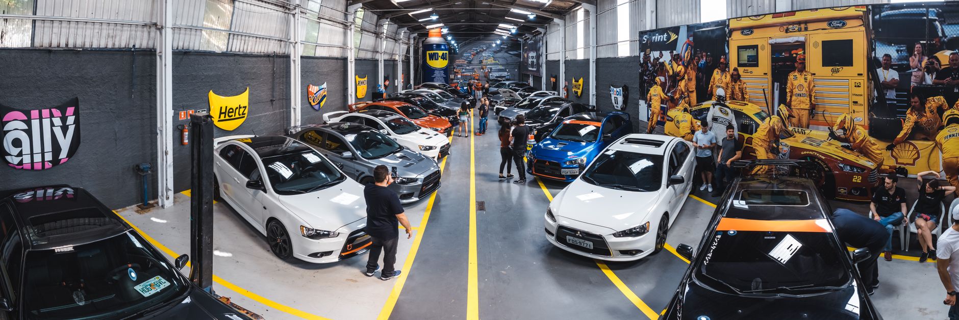 A vibrant scene of a car enthusiast gathering at Vila Nair, showcasing a variety of vehicles indoors.