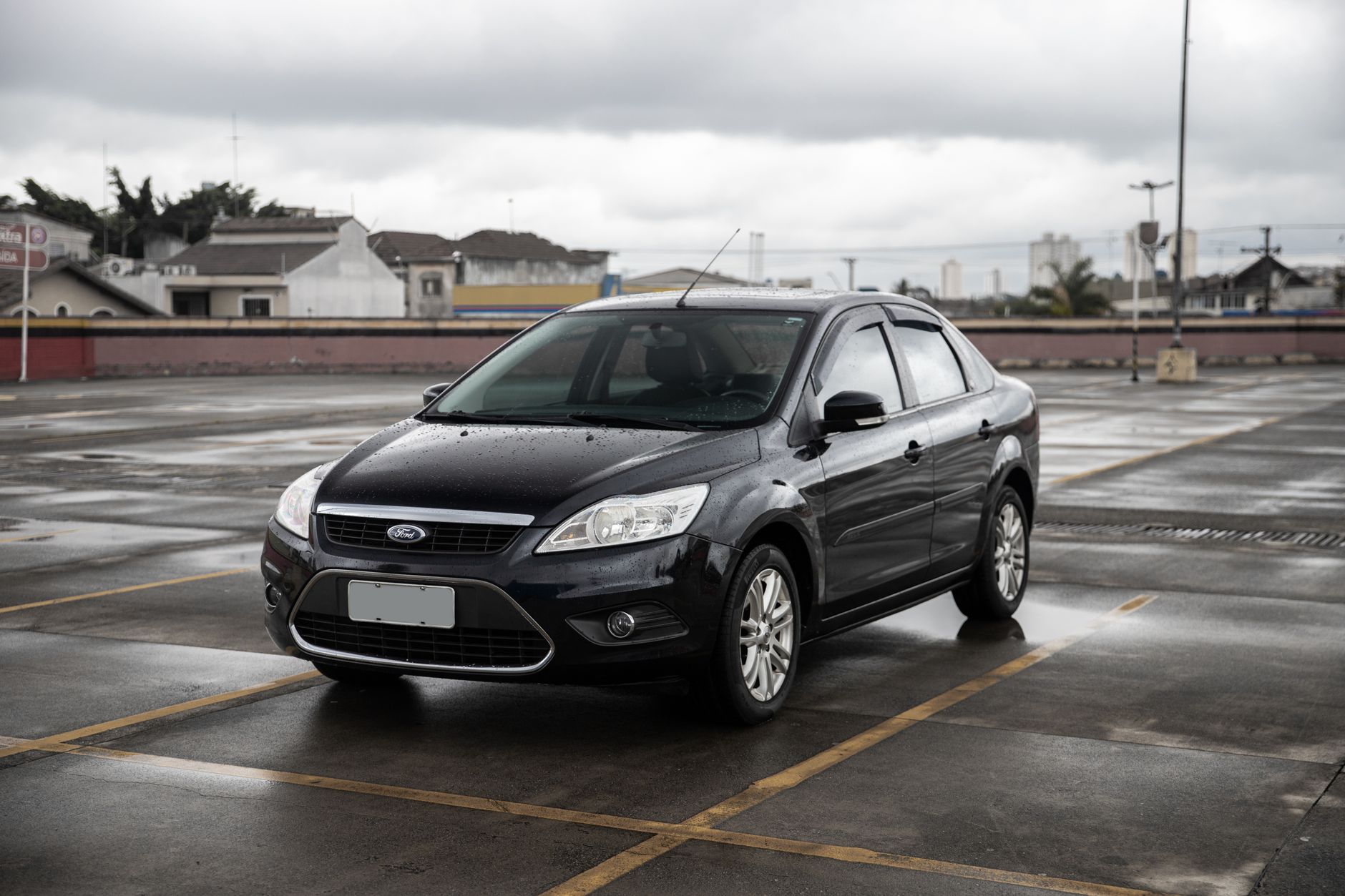 Black Ford sedan parked in a spacious São Paulo parking lot on a cloudy day.
