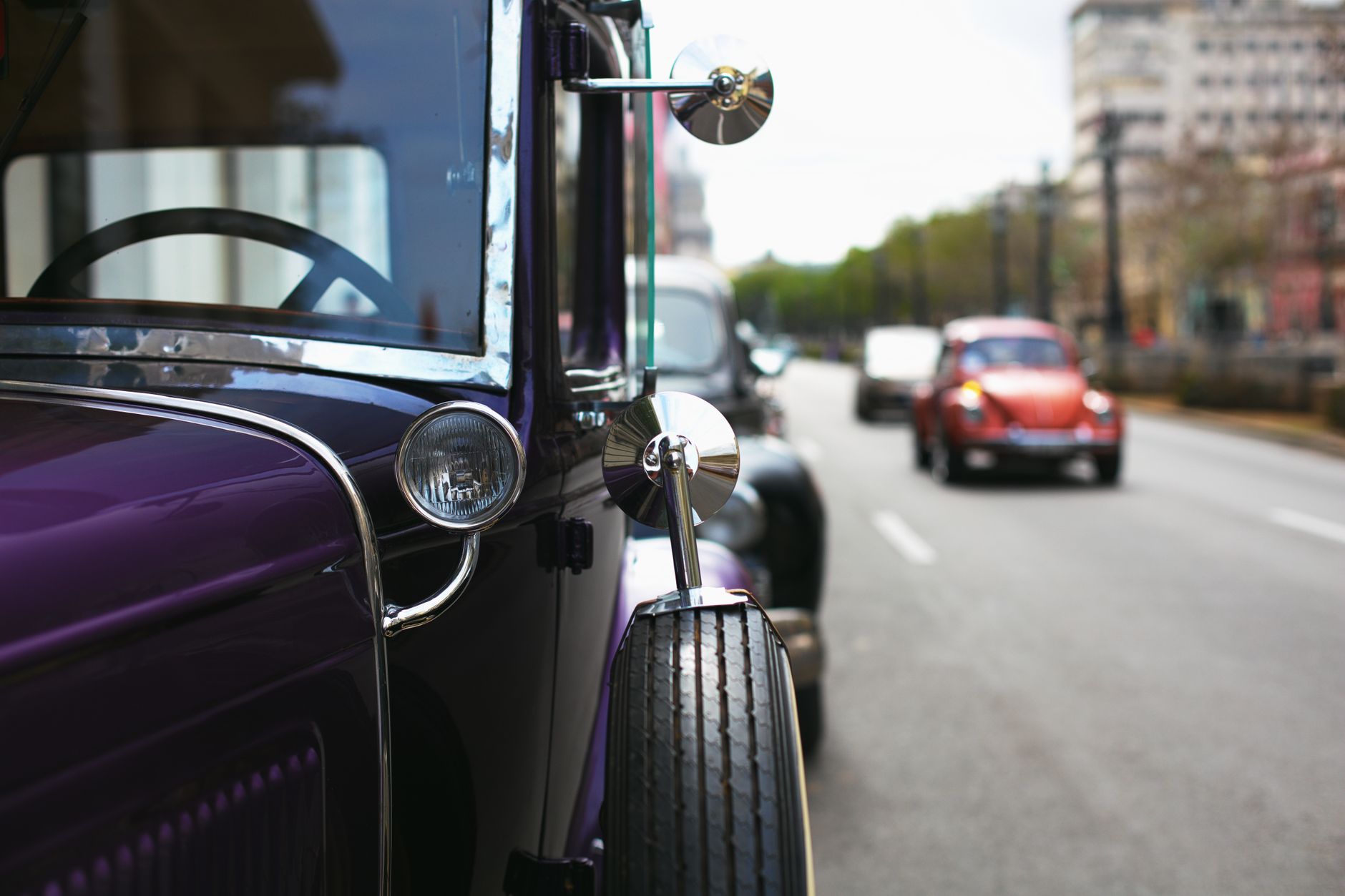 Detailed view of a purple vintage car with classic detailing, on a city street.