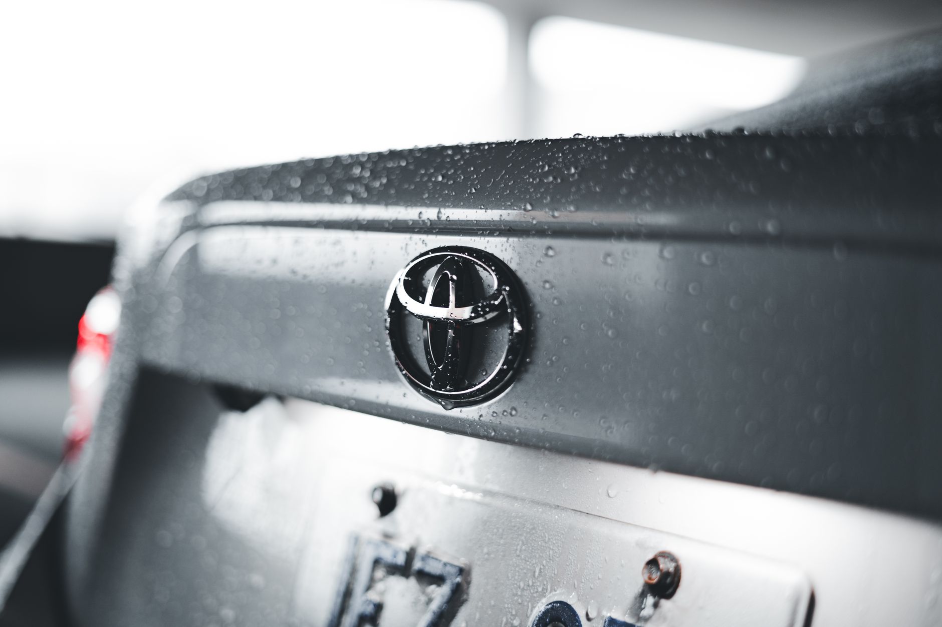 Detailed close-up of a raindrop-covered car emblem on a Toyota vehicle.