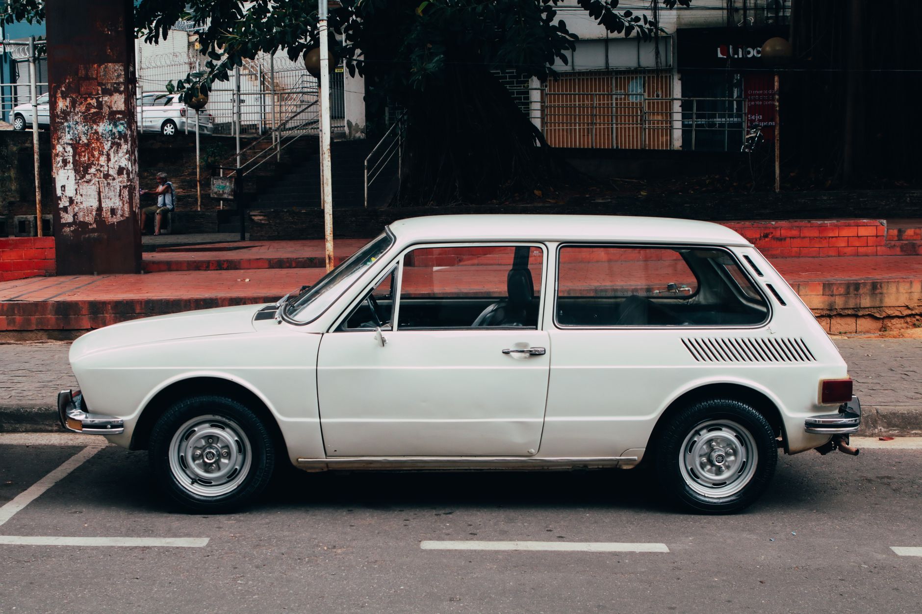 Classic white vintage car parked on an urban street during the day.