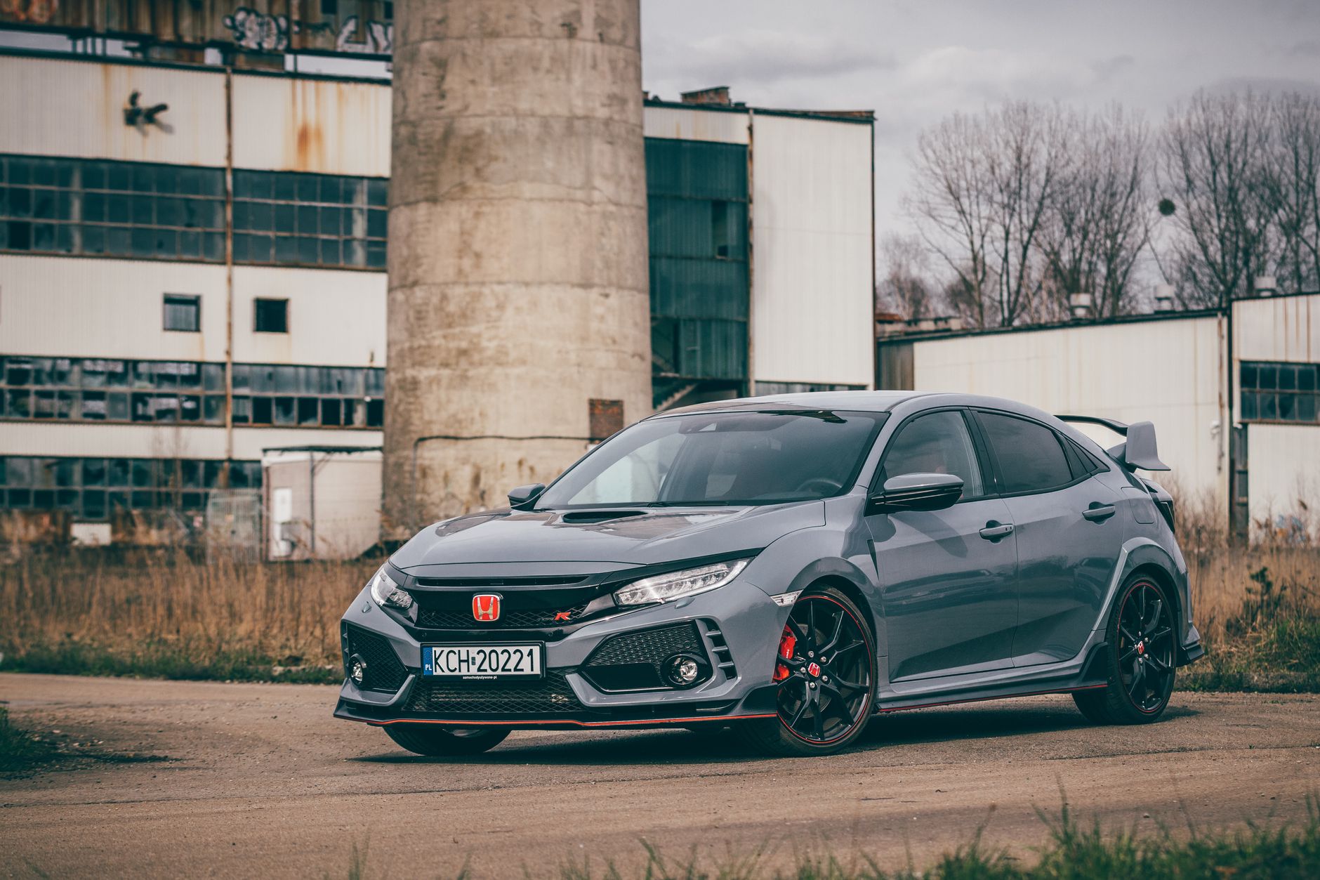 Gray Honda Civic Type R parked in front of an abandoned industrial building.