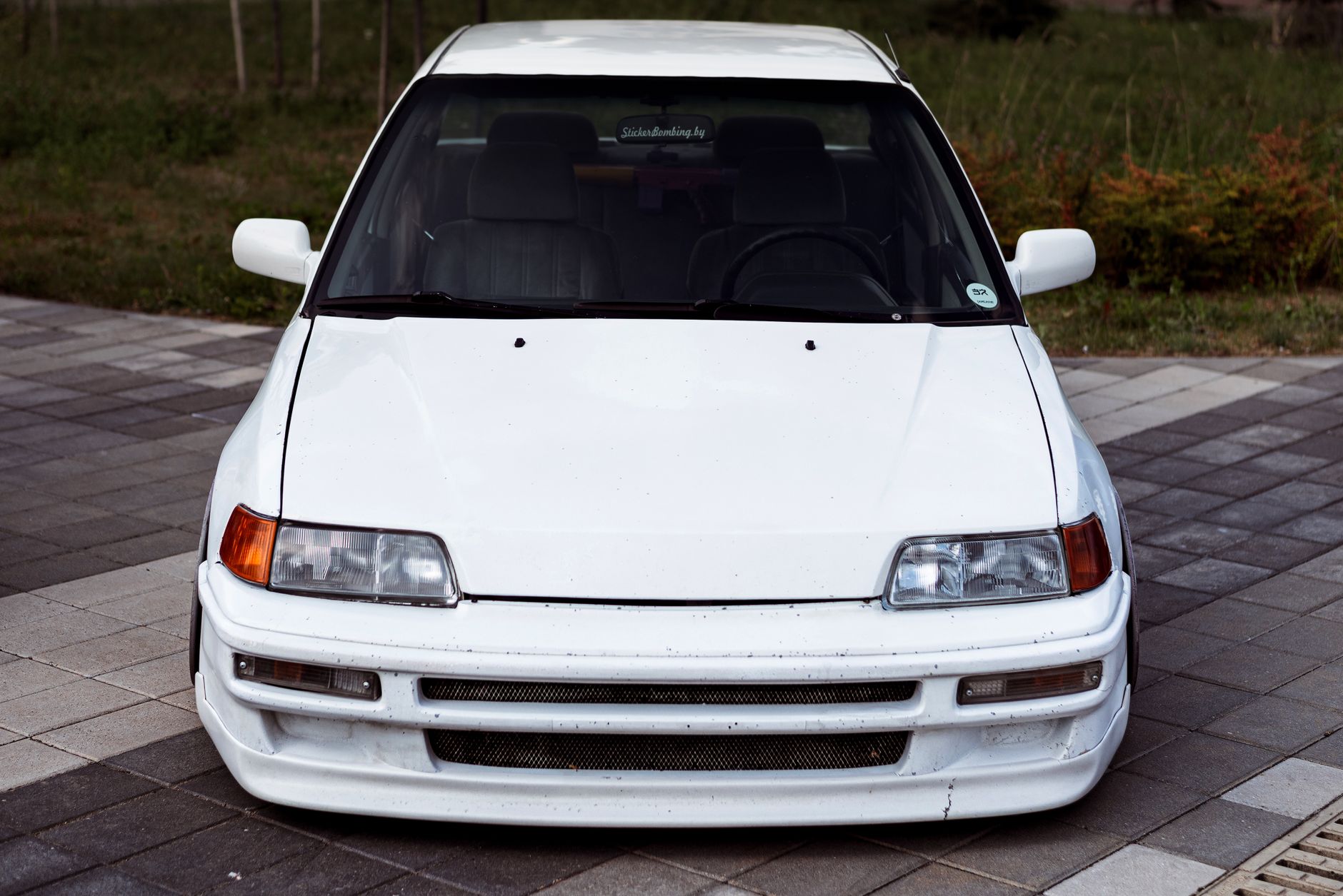 Front view of a white Honda Civic parked on a city pavement, showcasing sleek design.