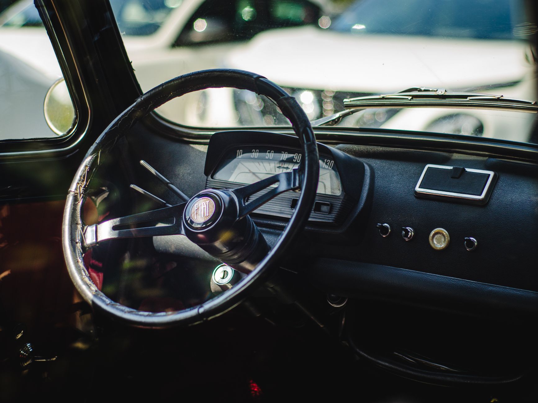 Close-up of a vintage Fiat 500 dashboard showcasing the steering wheel and speedometer.