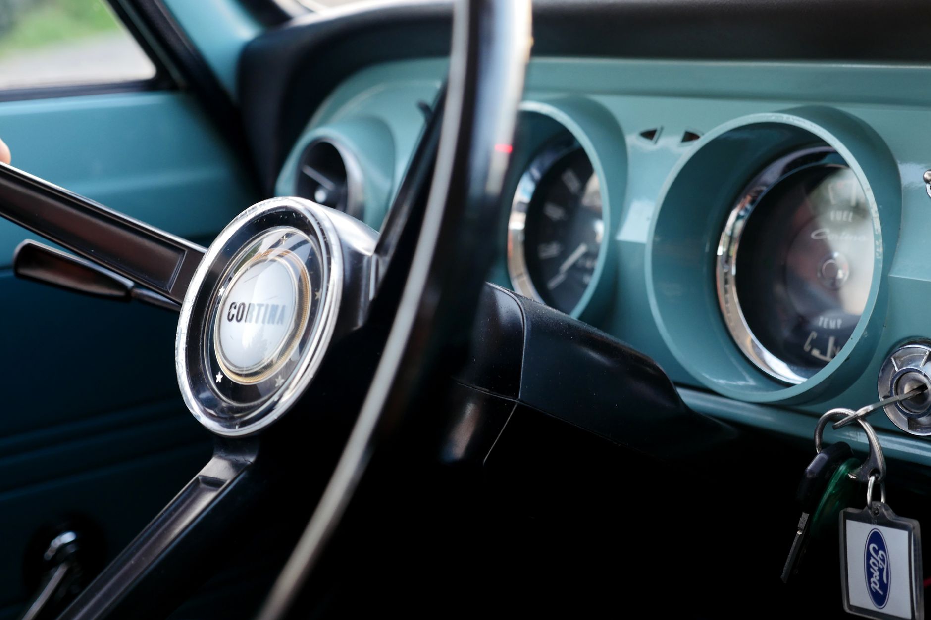 Close-up of vintage car steering wheel and dashboard featuring classic design elements.
