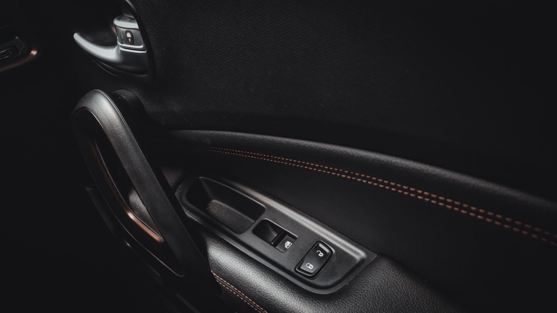 Detailed view of a car door interior showcasing handle and stitching.