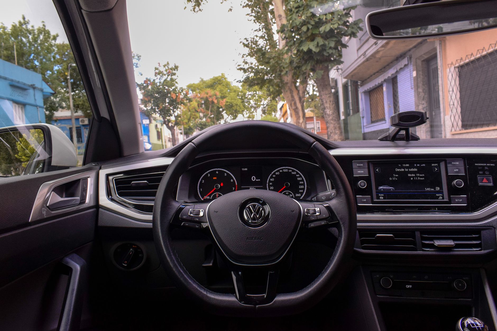 A view of a Volkswagen car interior highlighting the dashboard and steering wheel in an urban setting.