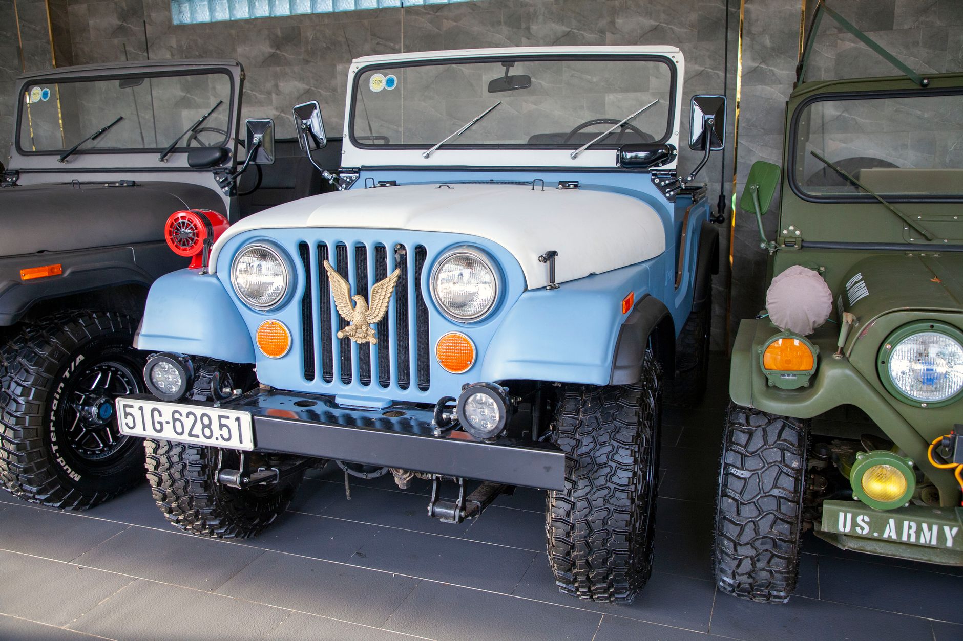 A collection of classic jeeps in an indoor setting, showcasing vintage military designs.