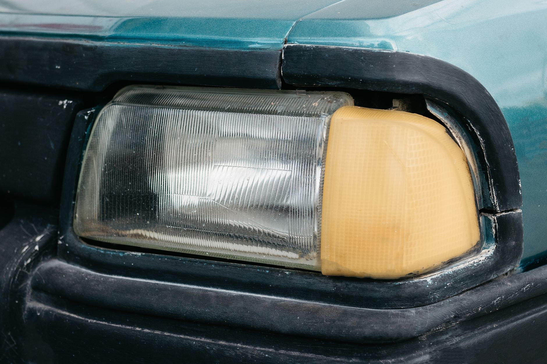 Detailed view of an old car's headlamp showing signs of wear and age.