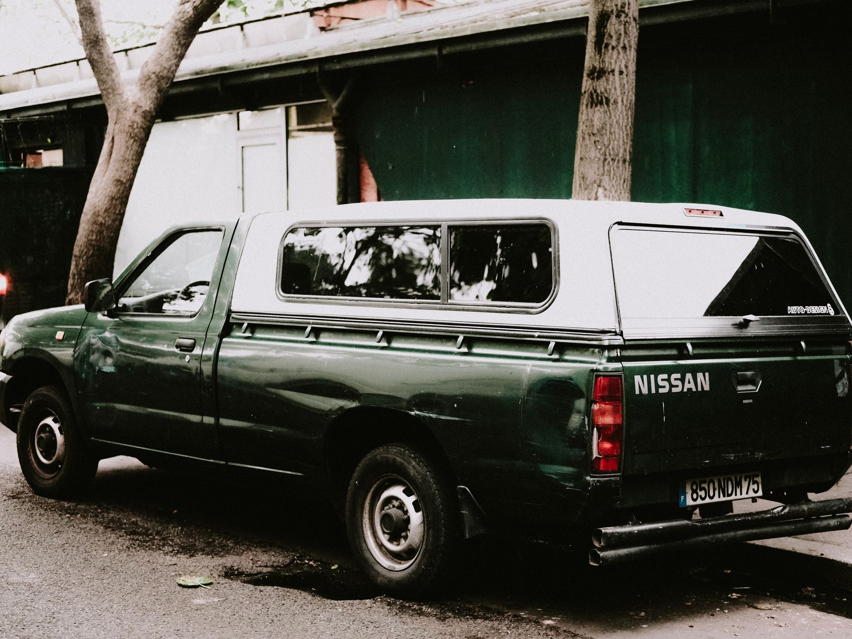 A green Nissan truck is parked on an urban street, showcasing its robust design.