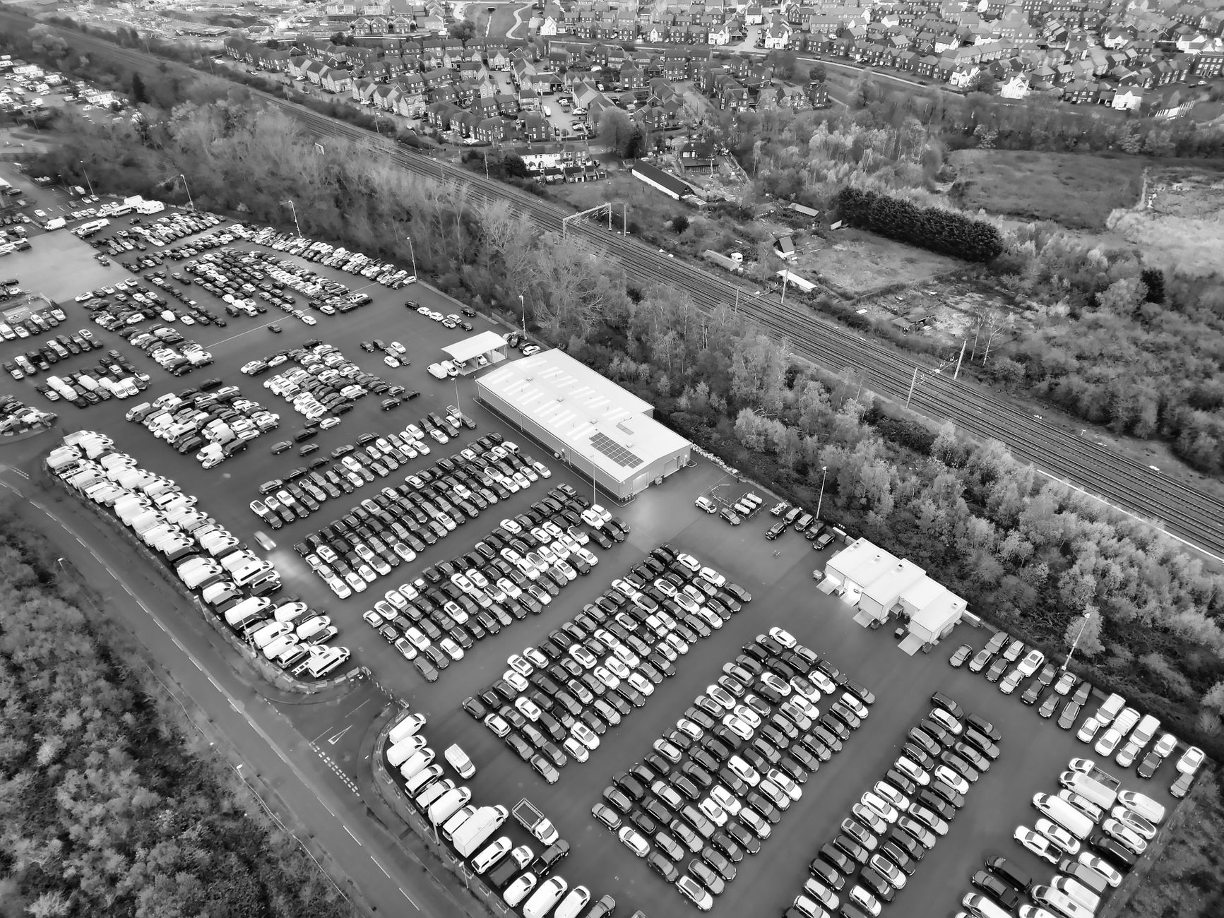 Black and white aerial view of a car parking lot and surrounding urban area.