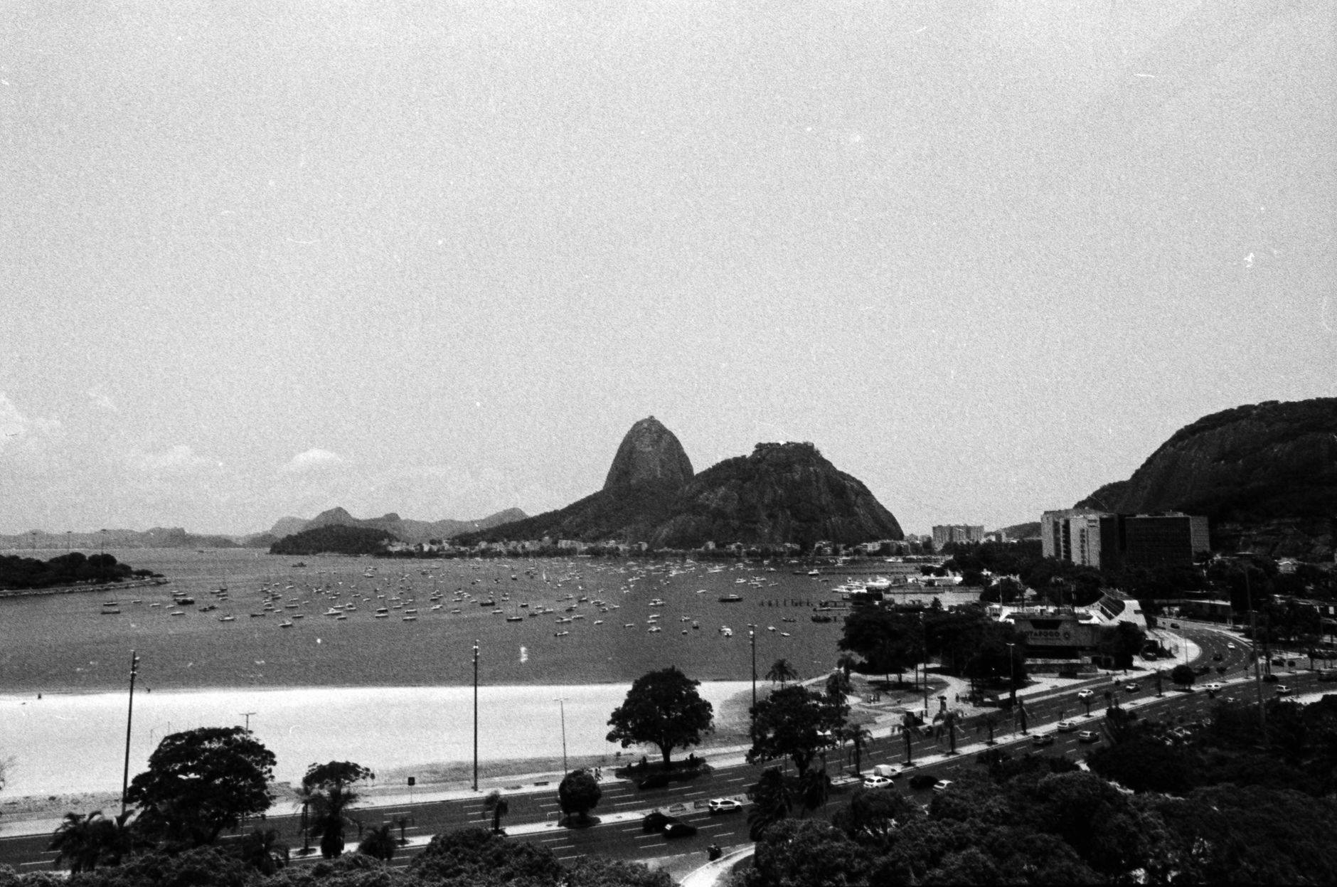 Black and white tropical shore of ocean with mountains and hotel buildings near ocean